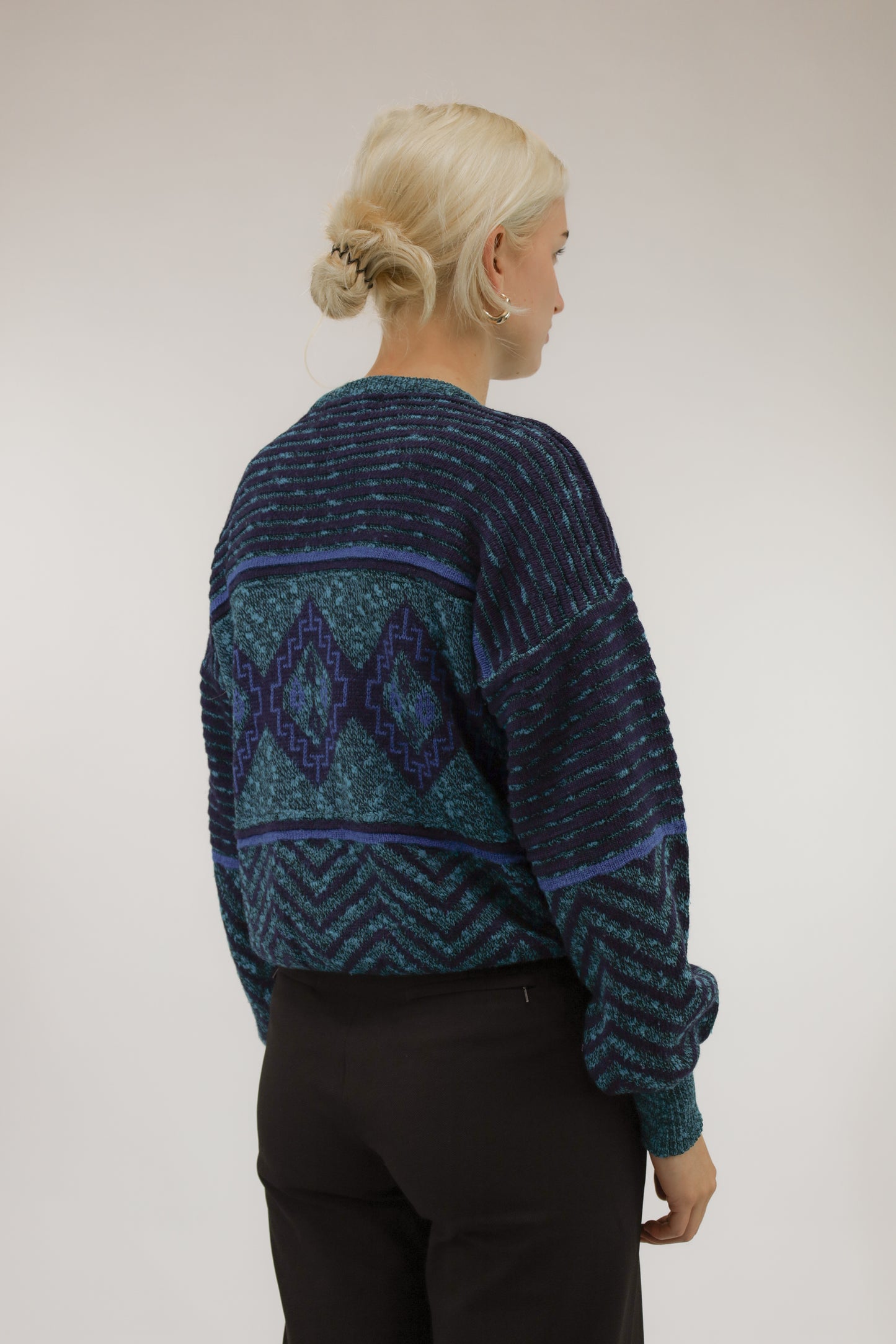 Model van achteren met vintage trui in blauw- en groentinten – oversized fit en stoere look.