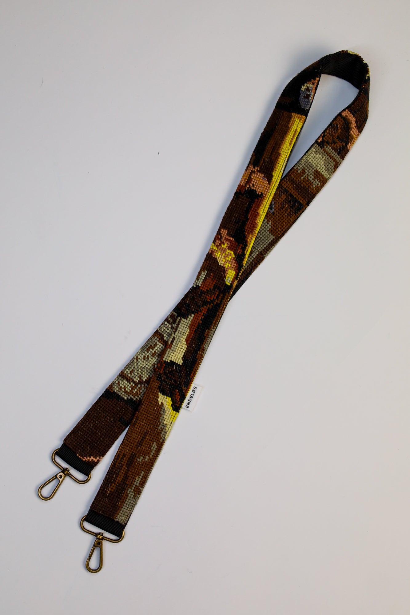 Strap made from an embroidered painting inspired by Rembrandt’s The Night Watch, featuring black, brown, grey, and yellow tones.