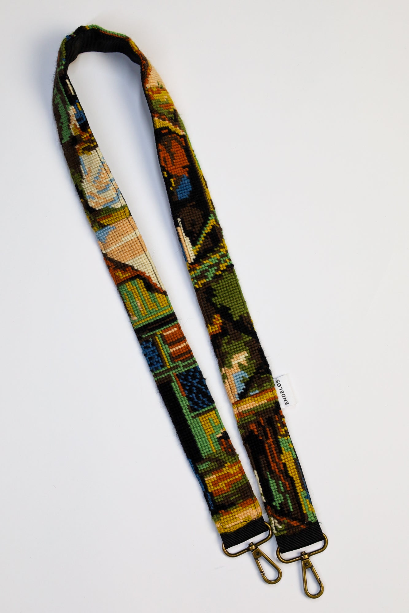 Close-up of a strap with an embroidery of rural life, in natural colors and made from upcycled materials.