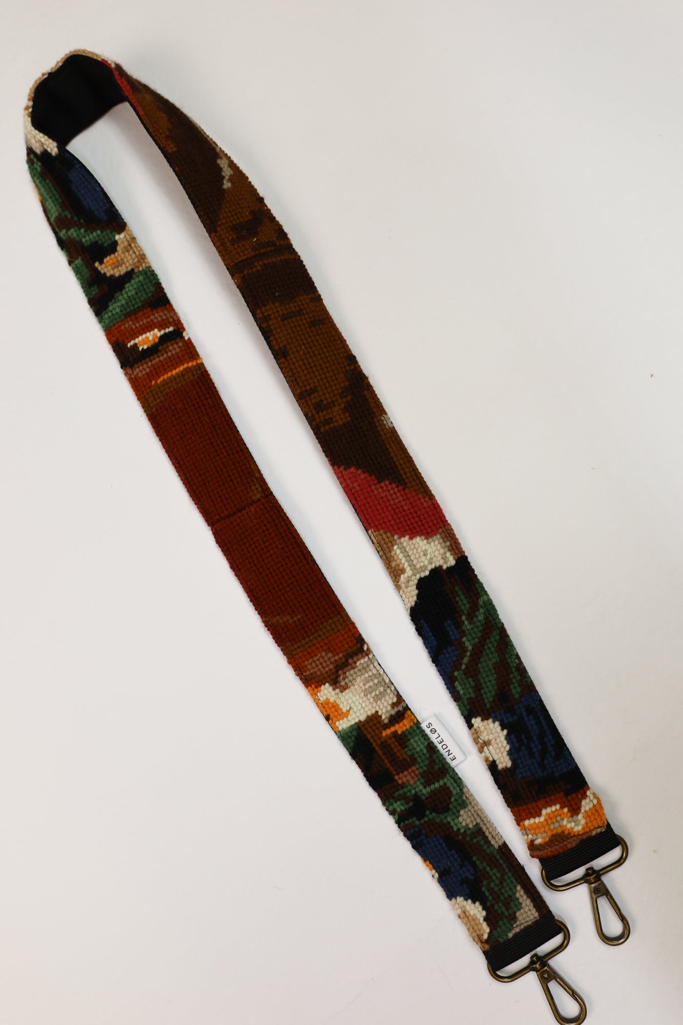 Detail van een strap met kleurcombinaties van bruin, groen, blauw, wit en geel, geïnspireerd door De Goudweger.