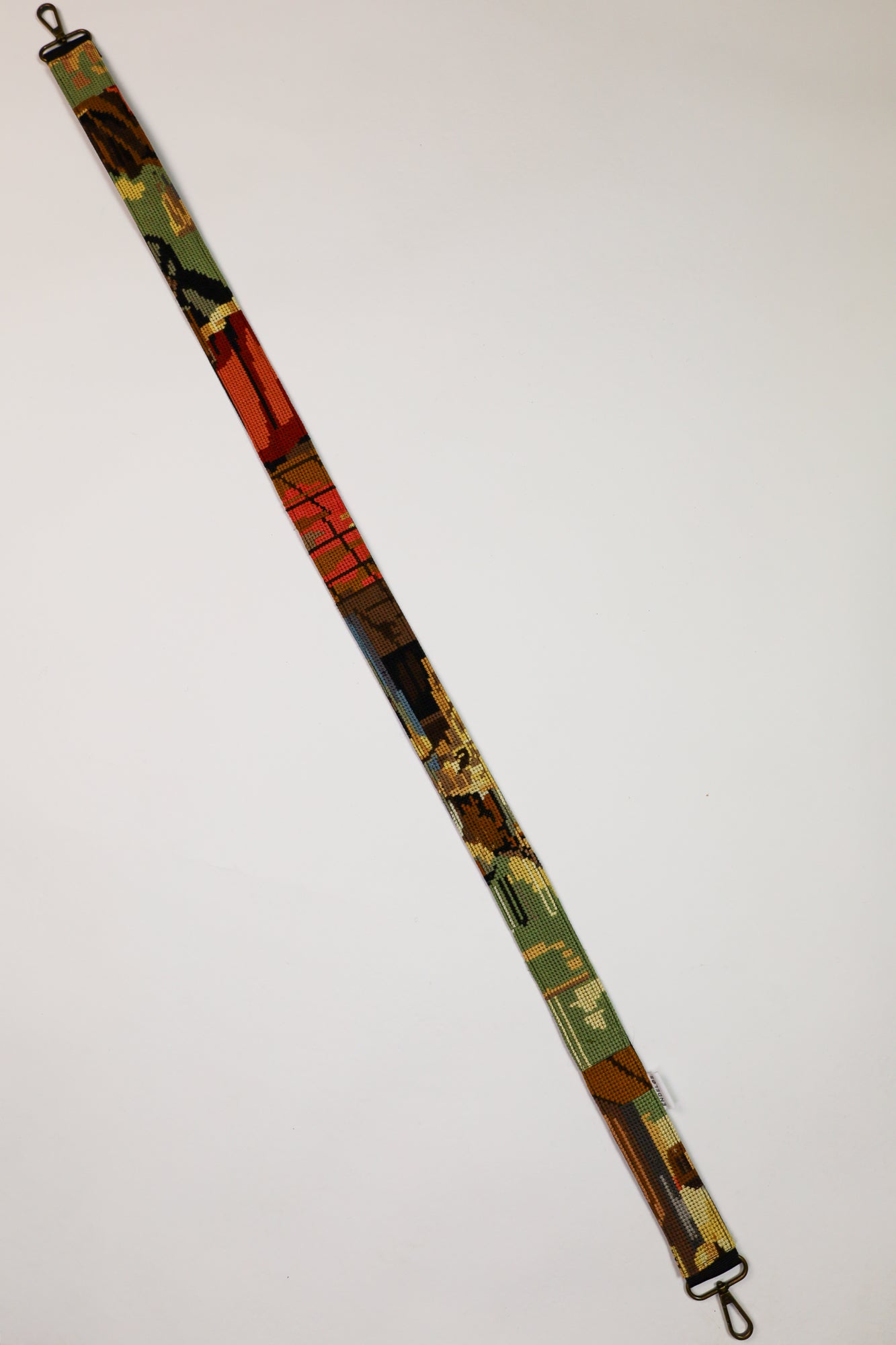 Sustainable strap in green, brown, and red tones, with embroidery depicting a hand-washing scene, suitable for bags, cameras, and phones.