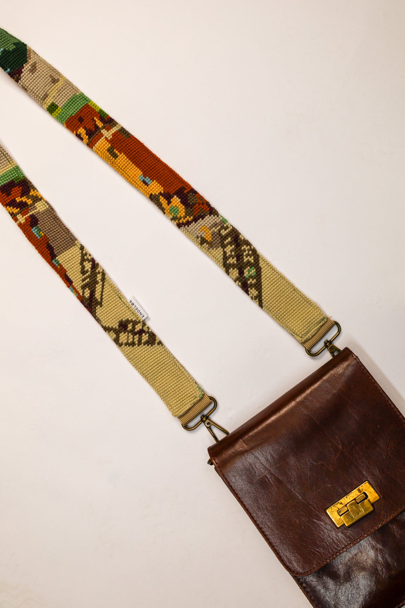 Handgemaakte tasband bevestigd aan een tas, gemaakt van vintage geborduurd schilderij.