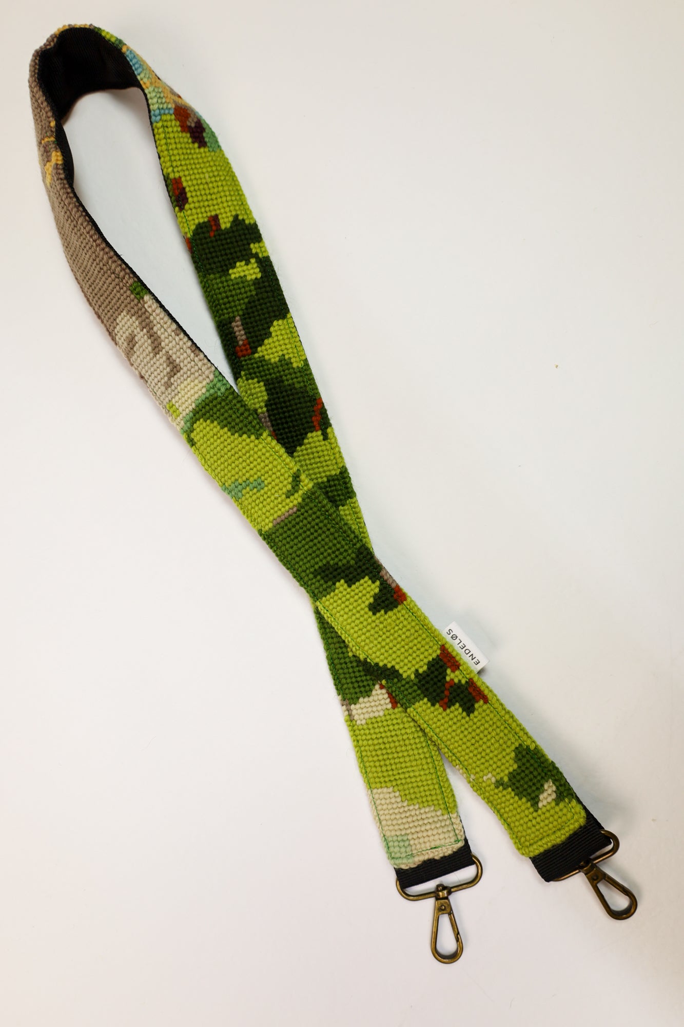 Sustainable strap with a colorful embroidered pattern in green tones, suitable for bags, cameras, and phones.