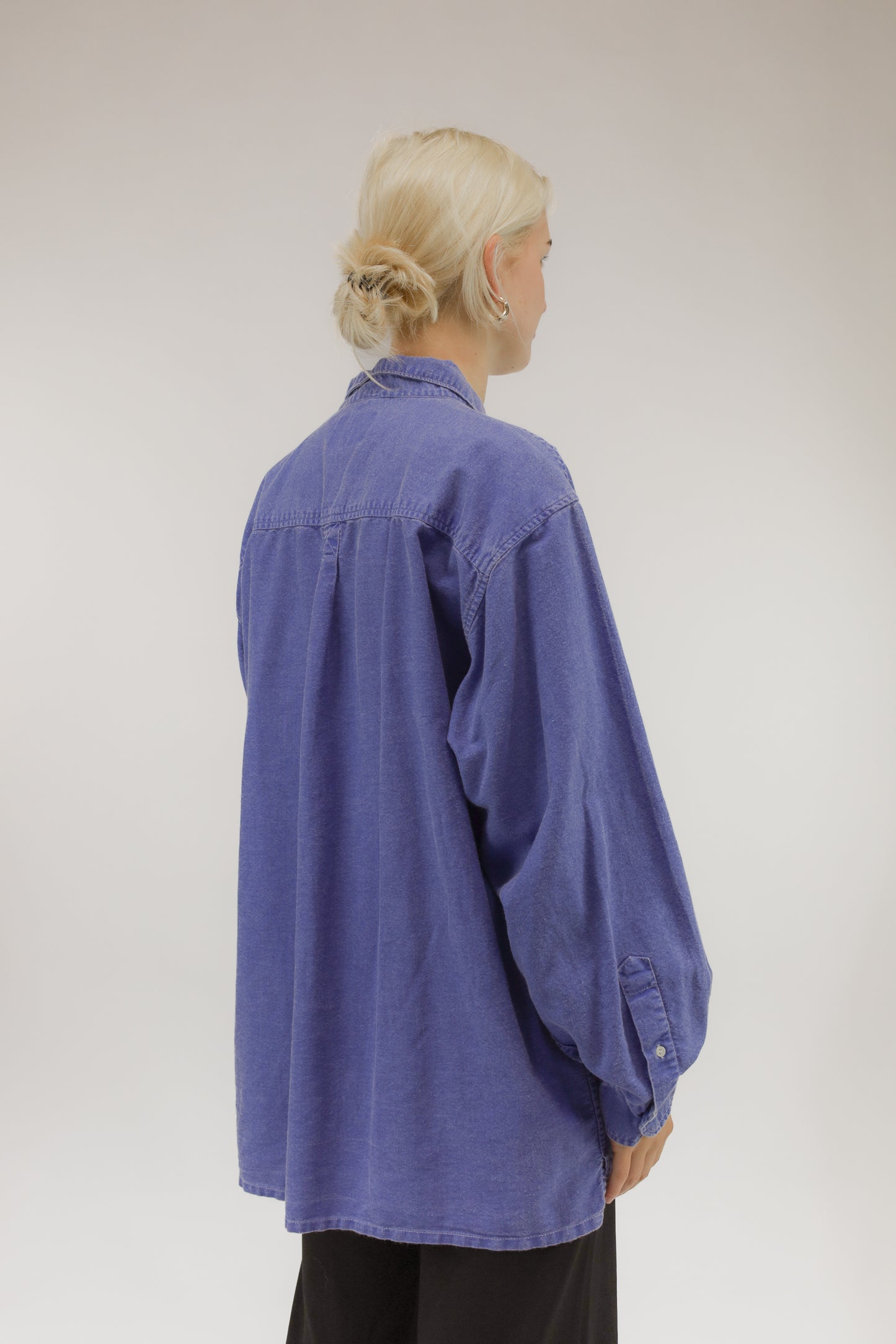 Model van achteren met vintage oversized blouse van dun katoen met denim verwassen effect.