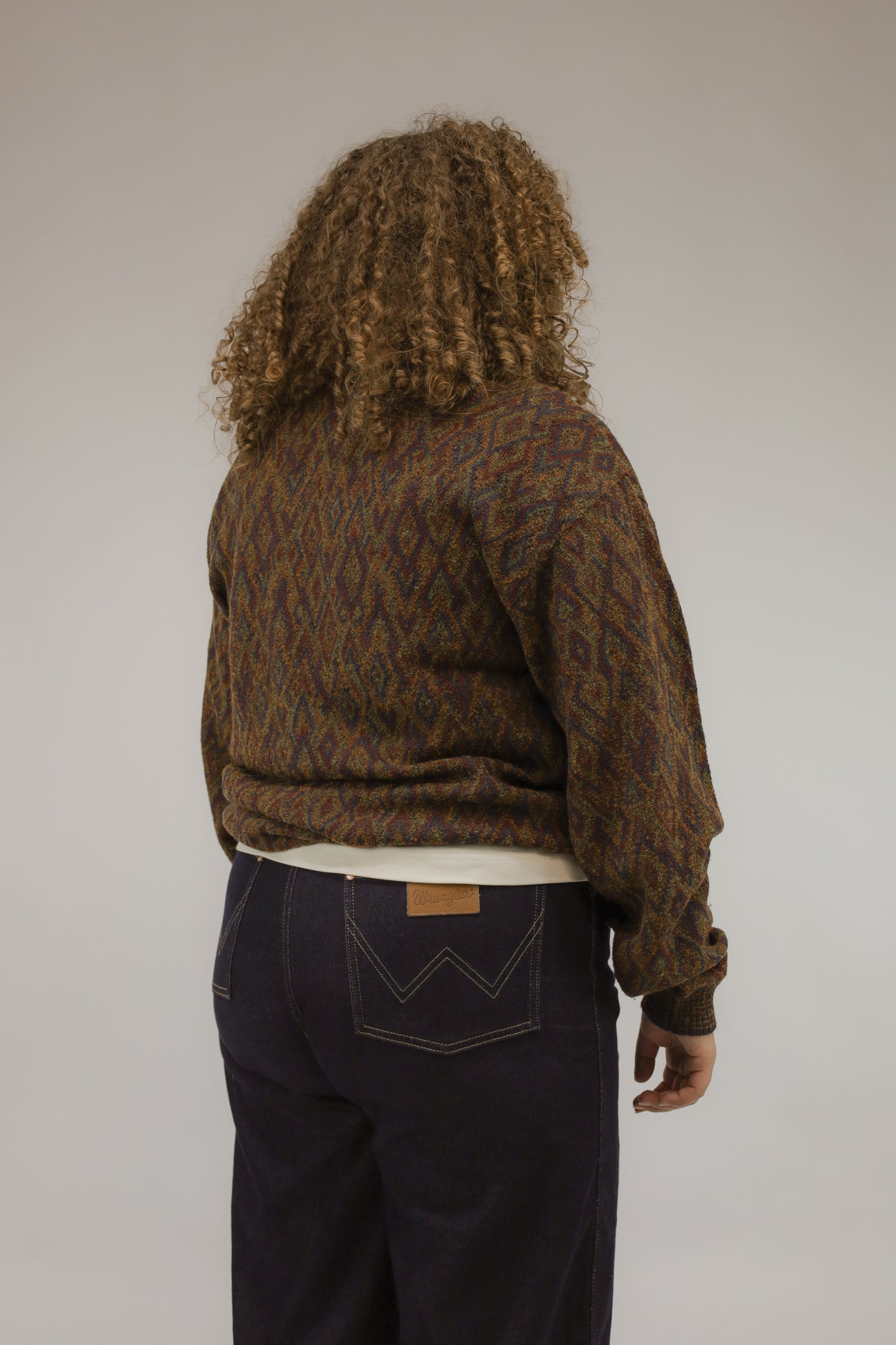 Model van achteren met vintage meerkleurige gebreide trui met grafisch patroon.