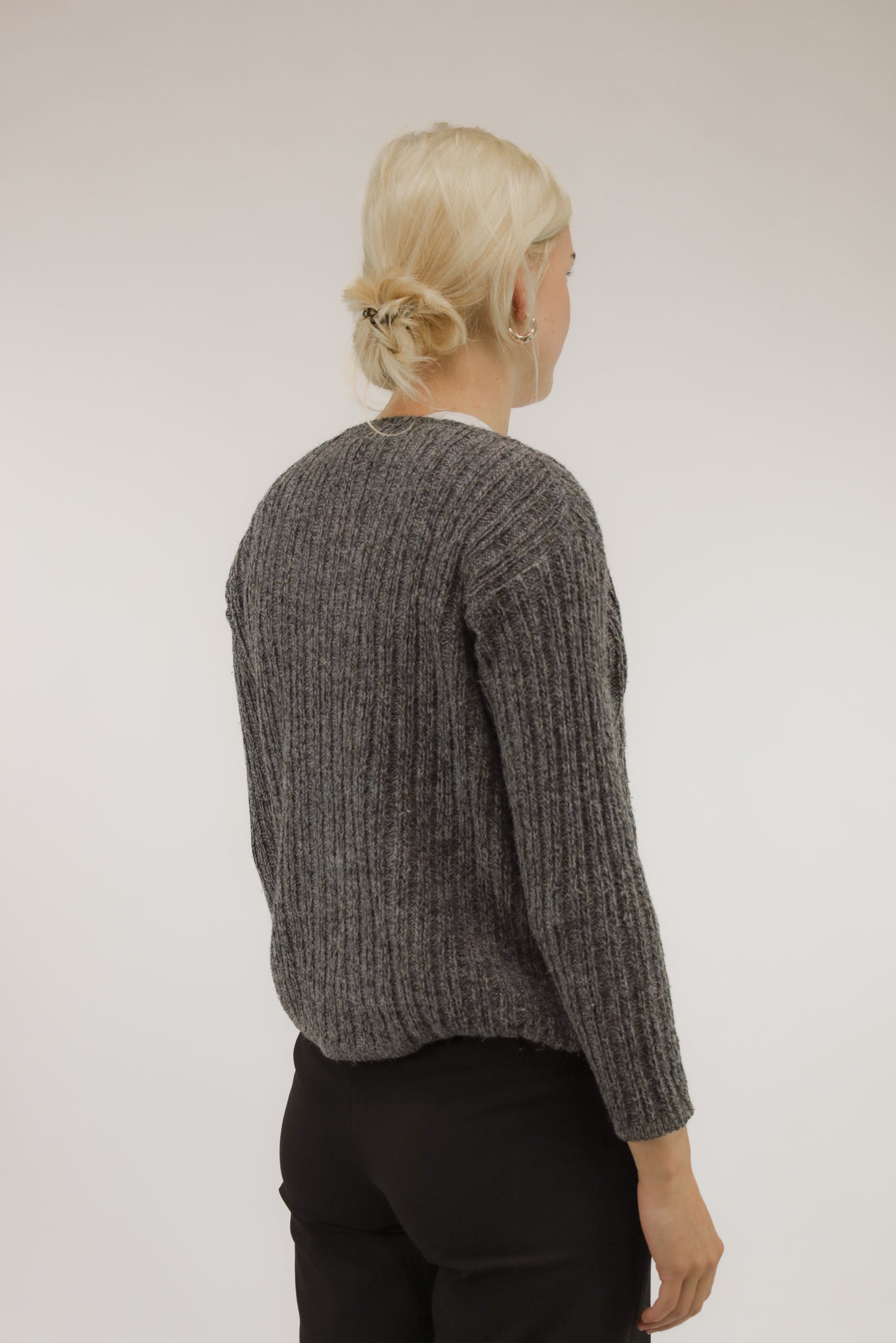 Achteraanzicht van model met fijngebreide vintage trui in grijs- en blauwtinten van mohair- en alpacamix.