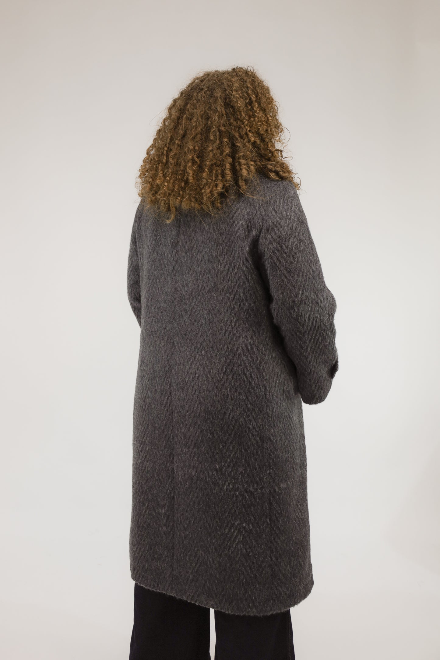 Achteraanzicht van model met blauwgrijze vintage jas van alpaca en merinoswol.