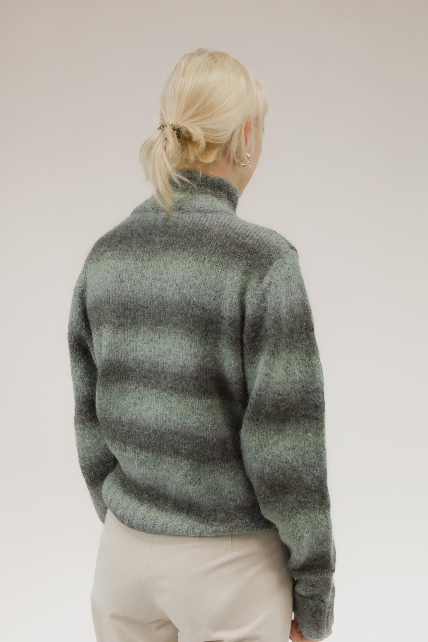 Achteraanzicht van model met ruimvallende groen-grijze vintage trui van mohairmix.