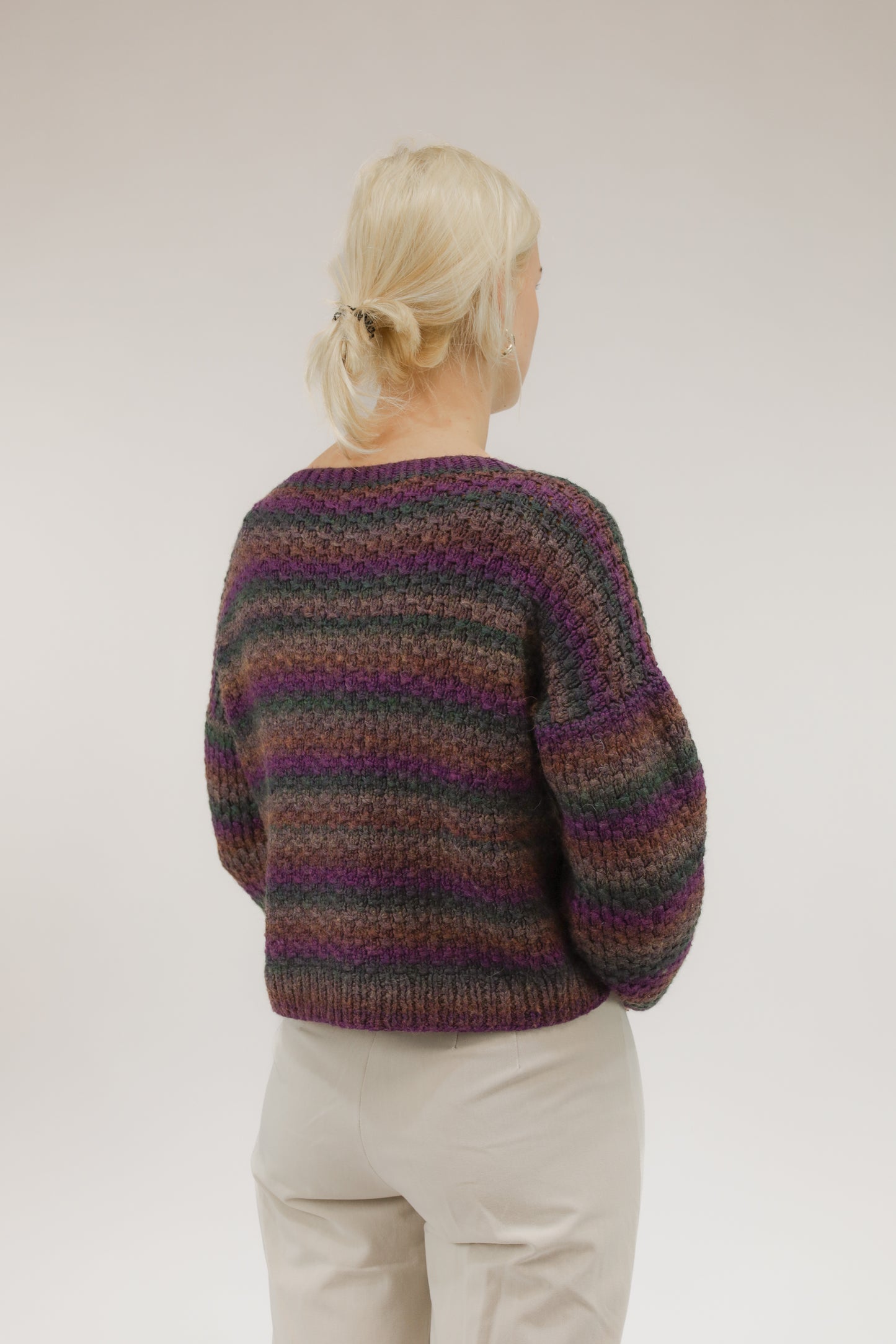 Model van achteren met cropped grofgebreide vintage trui – streepdessin en relaxed fit zichtbaar.