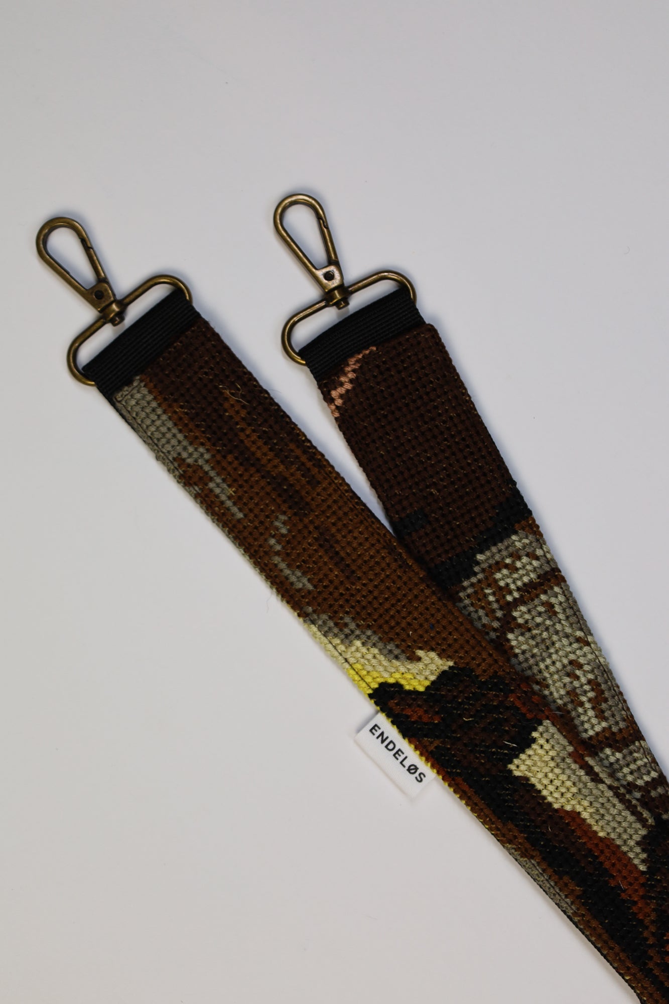 Artistieke strap in zwart, bruin, grijs en geel, gemaakt van een geborduurd schilderij en duurzaam hergebruikt materiaal.