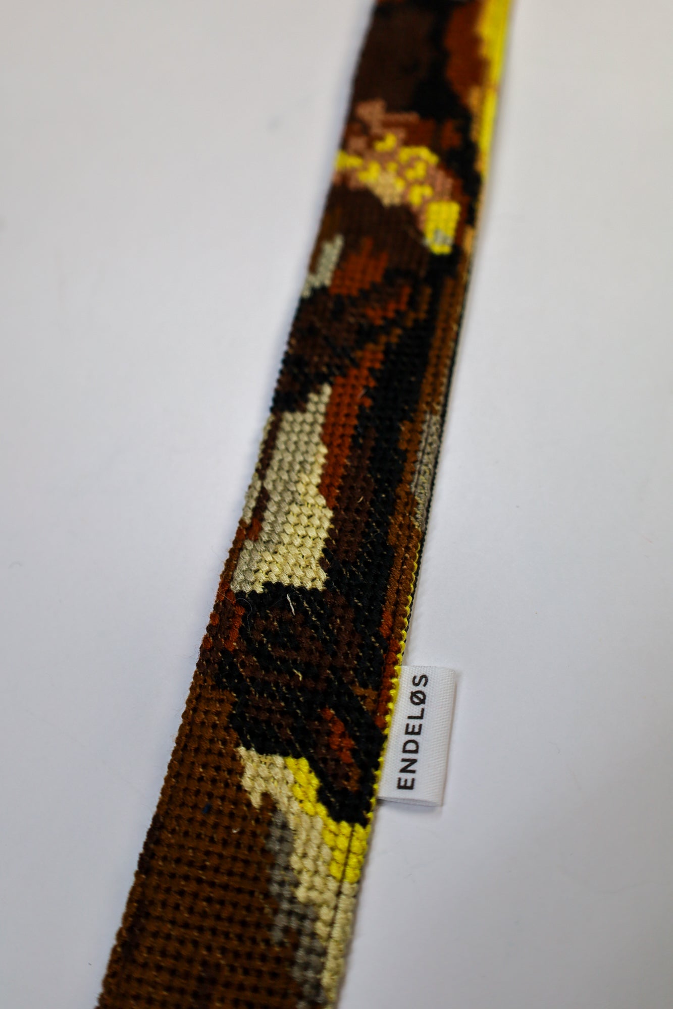 Close-up of a strap with warm colors and a pattern inspired by The Night Watch, crafted from upcycled materials.