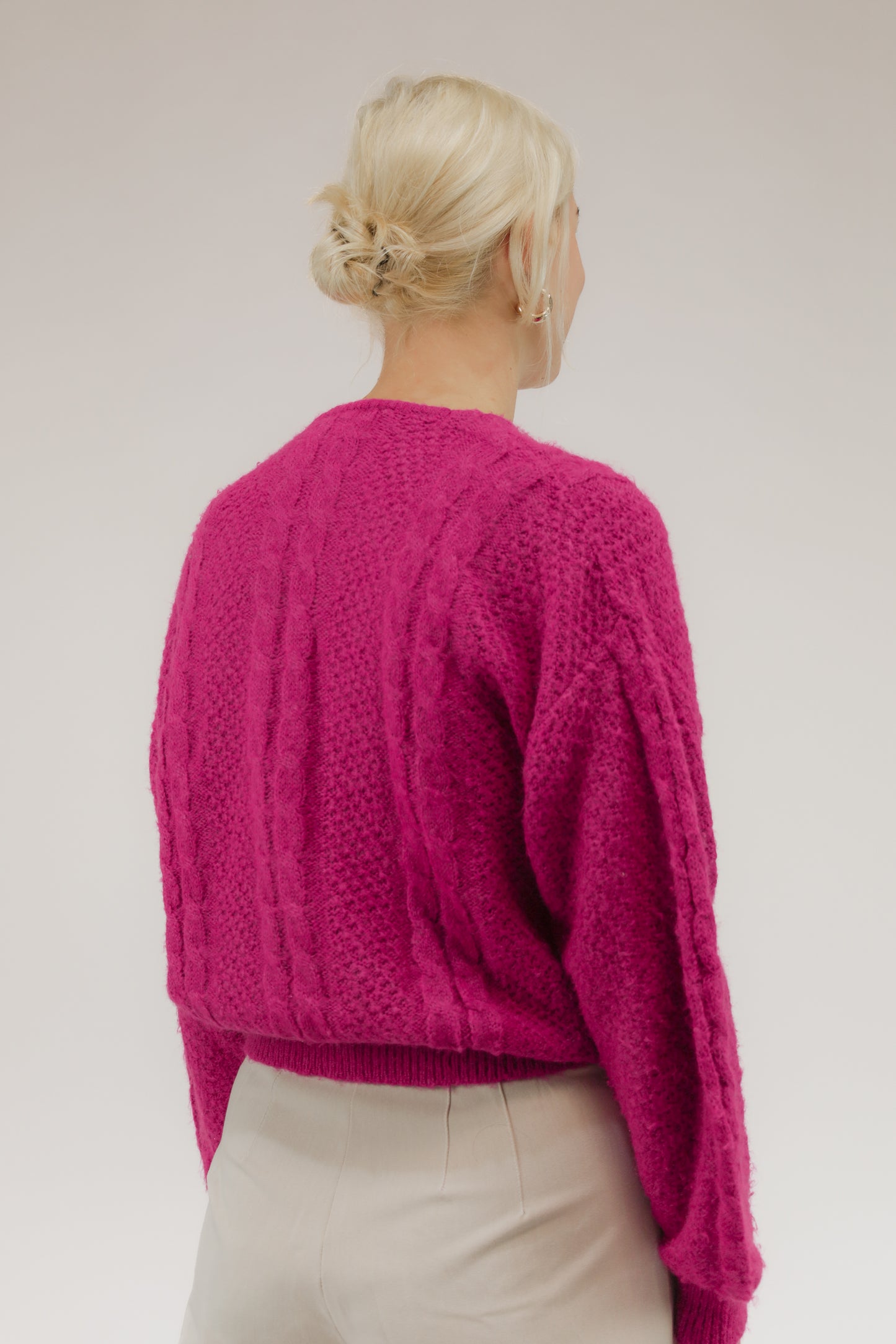 Model van achteren met zuurstokroze vintage trui – ronde halslijn en lichte breistructuur.