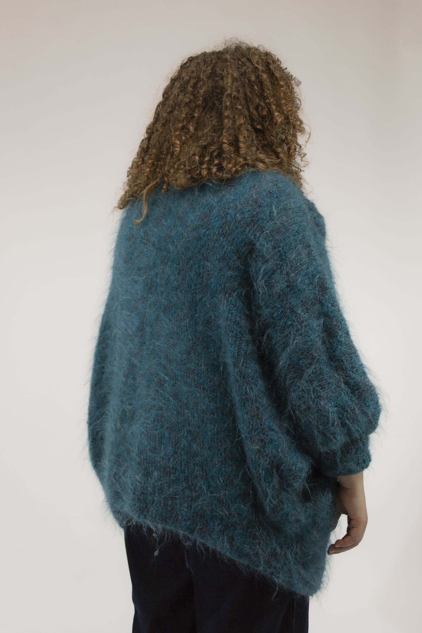 Model van achteren met oversized turkooisgroene vintage knit – wijde pasvorm en cozy look.