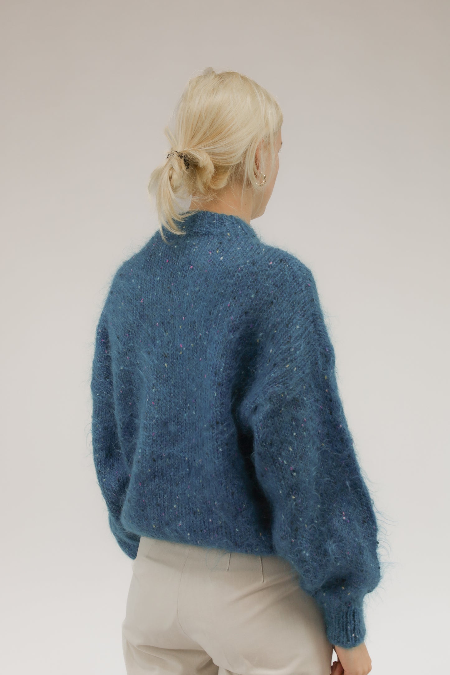 Model van achteren met vintage handgebreid turquoise vest in melange met bolletjespatroon.