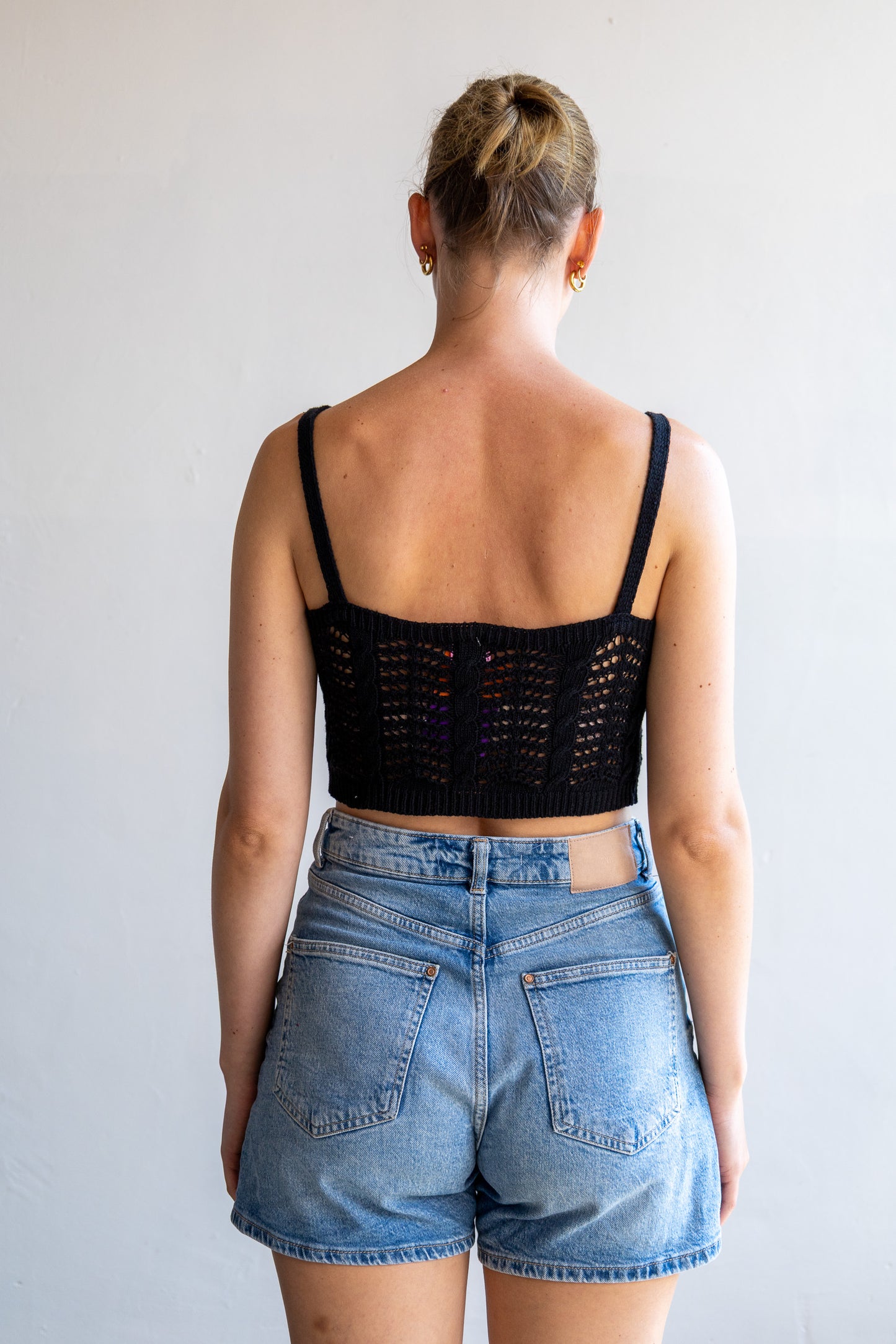 Achterzijde van de vintage zwarte open gebreide cropped top met luchtig breipatroon.