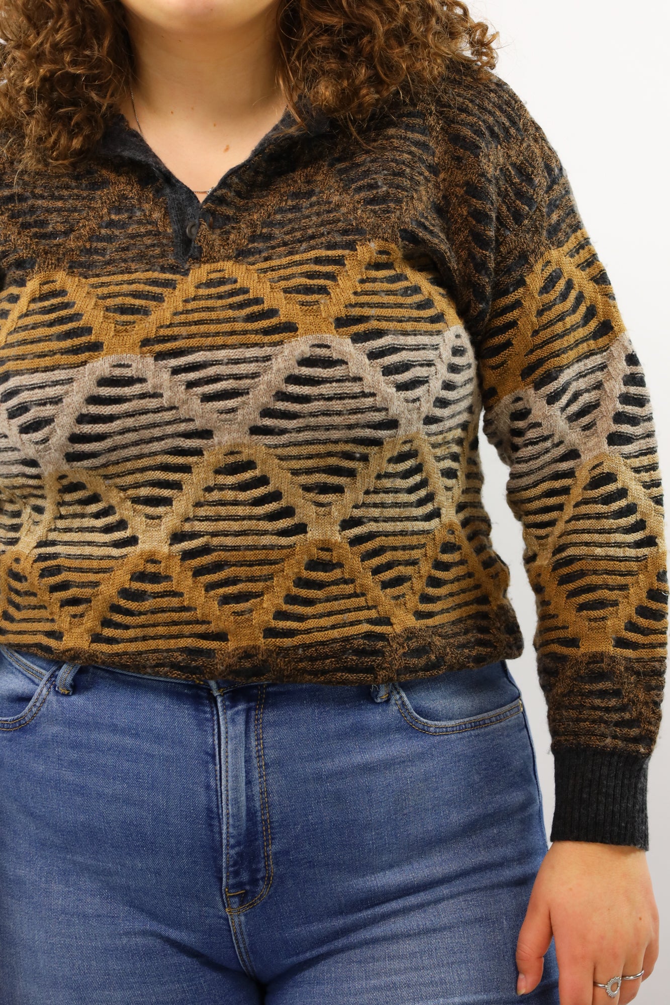 Detail van de ingeweven geometrische print op een donkergrijze vintage trui.