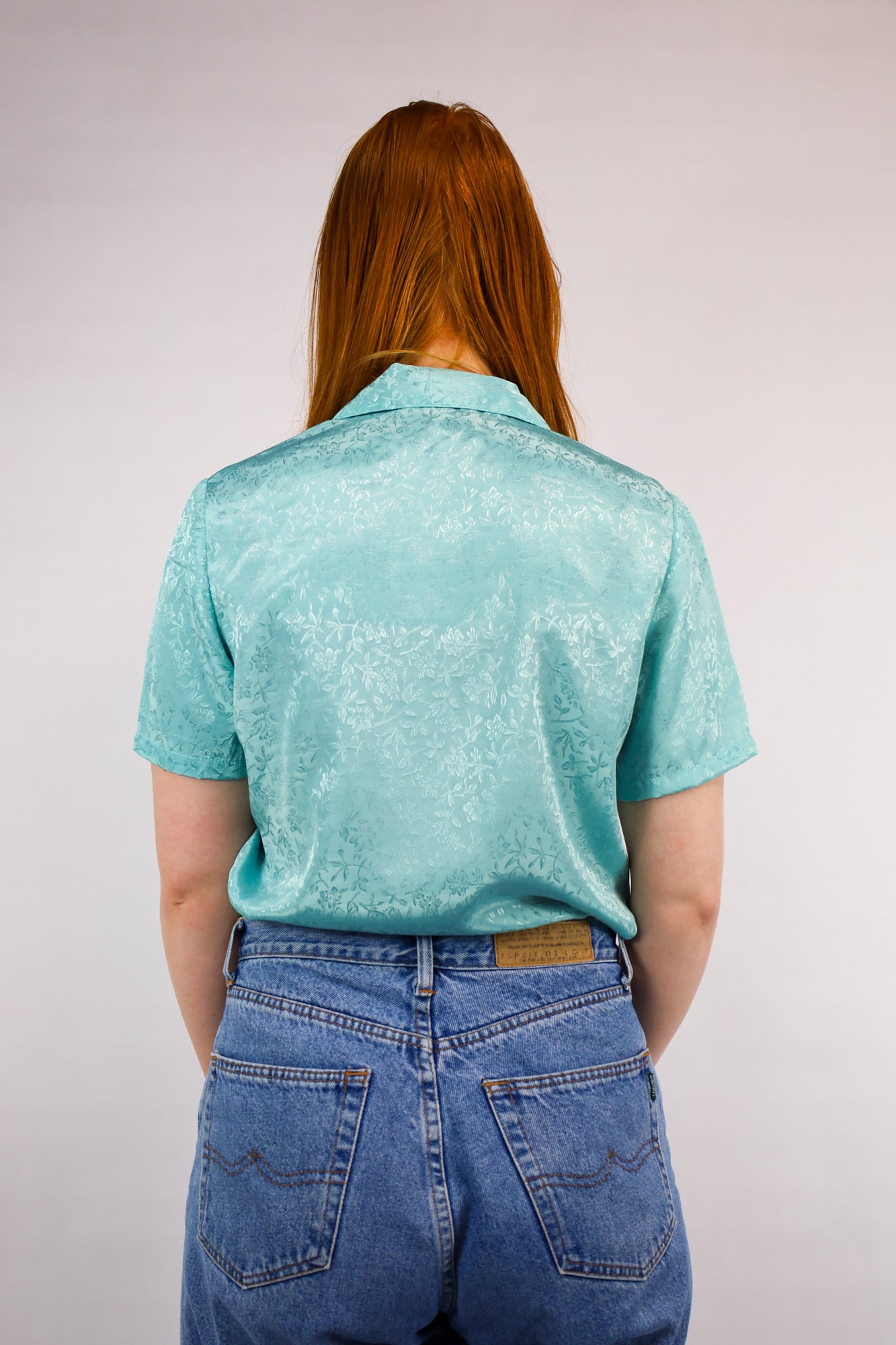 Achterkant van soepelvallende blouse in frisse aqua tint