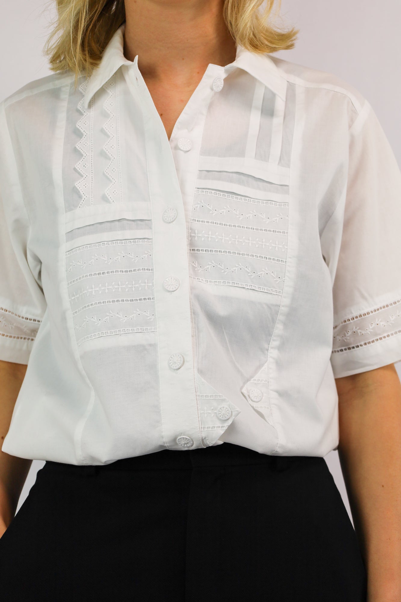 Detailfoto van kanten mouwafwerking en knoopsluiting