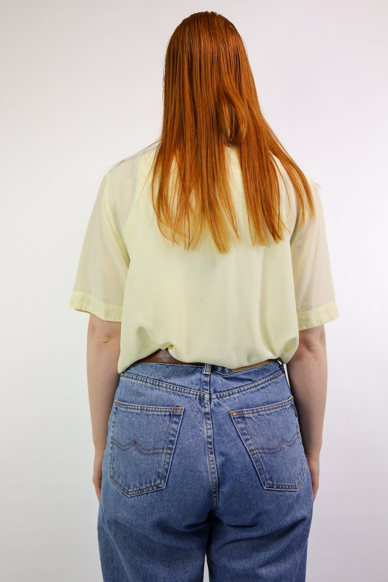 Achterkant van soepelvallende zijden blouse in zachte gele tint