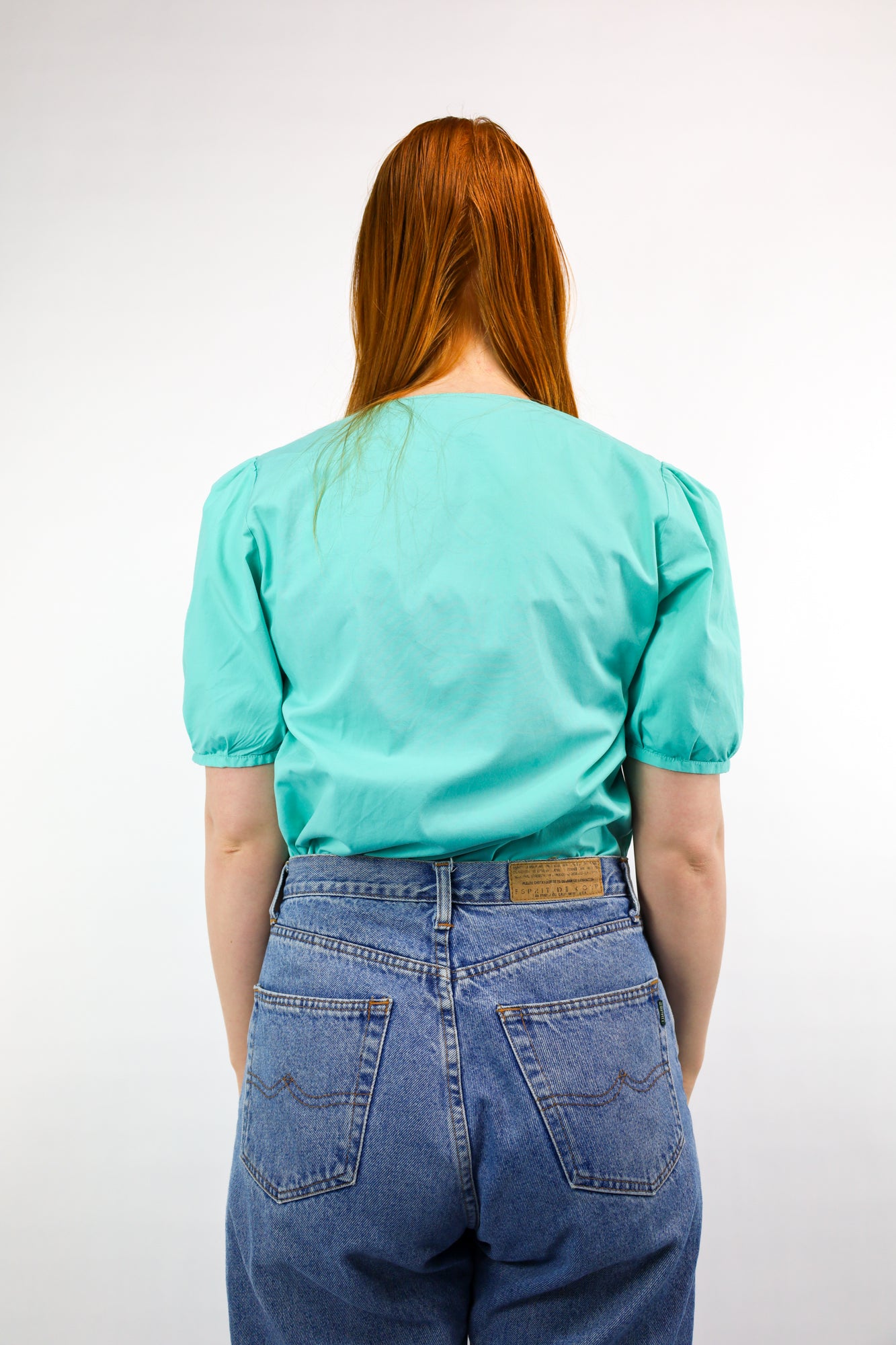 Achterkant van katoenen blouse in frisse turquoise kleur met vrouwelijke pasvorm