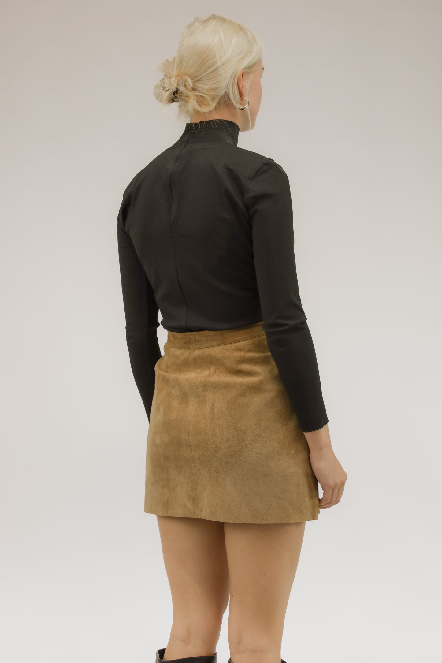 Model van achteren met vintage suède rok – glad silhouet en luxe afwerking.