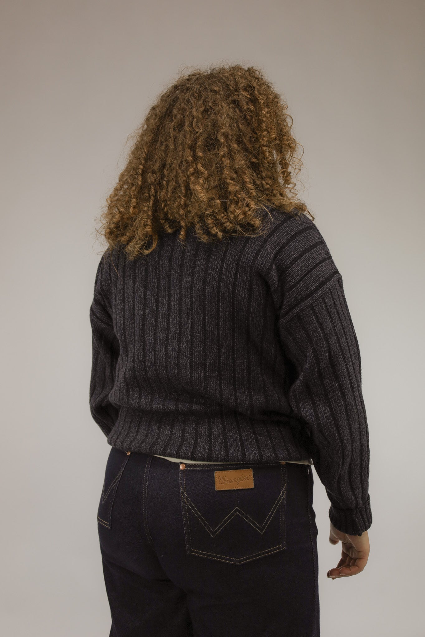 Model van achteren met oversized vintage trui in paars en donkerblauw – grafisch motief over de rug.