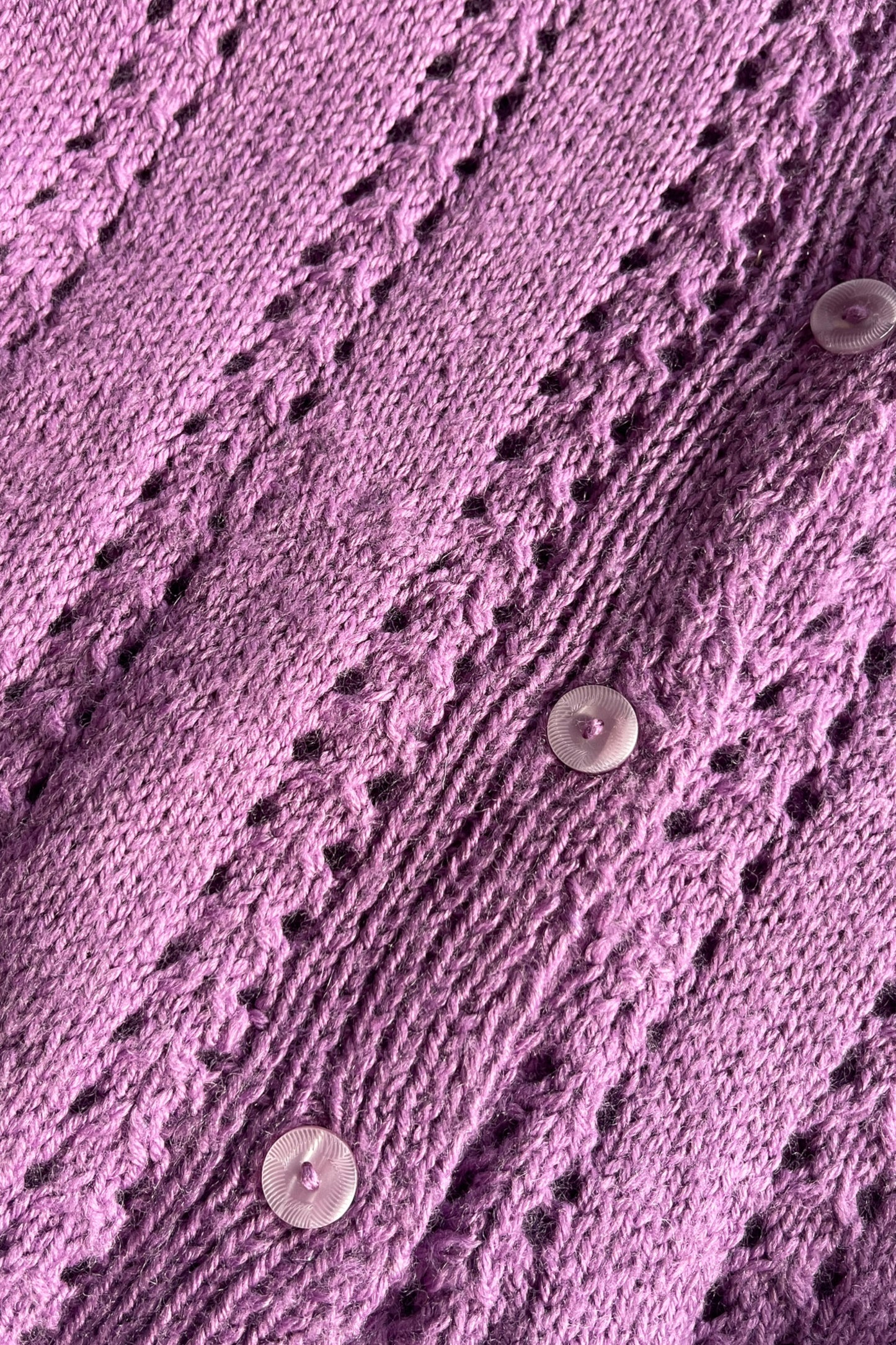 detail shot van materiaal- gebreid paars vest met glasknopen