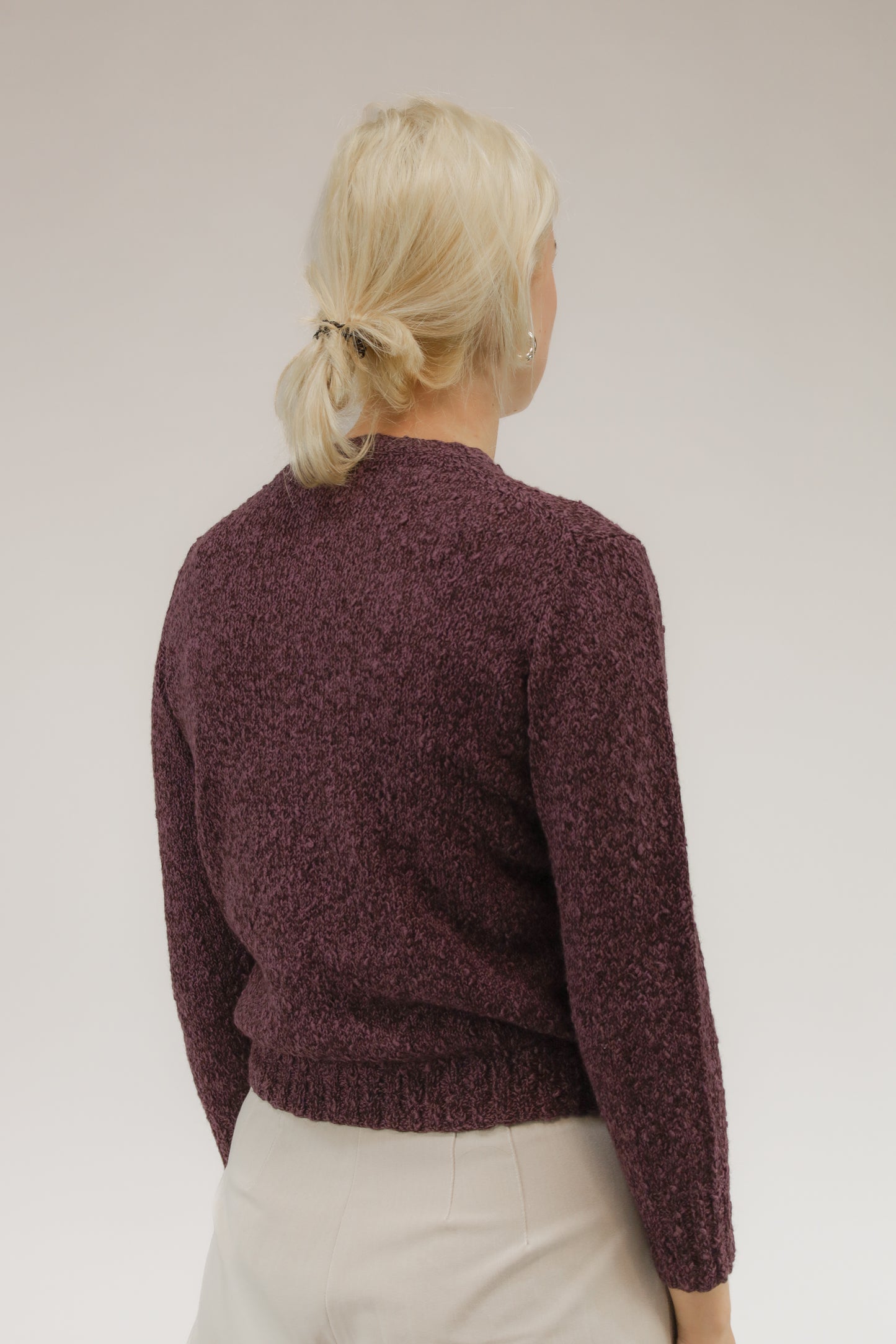 Achteraanzicht van model met fijngebreide vintage trui in paars gemêleerd garen.