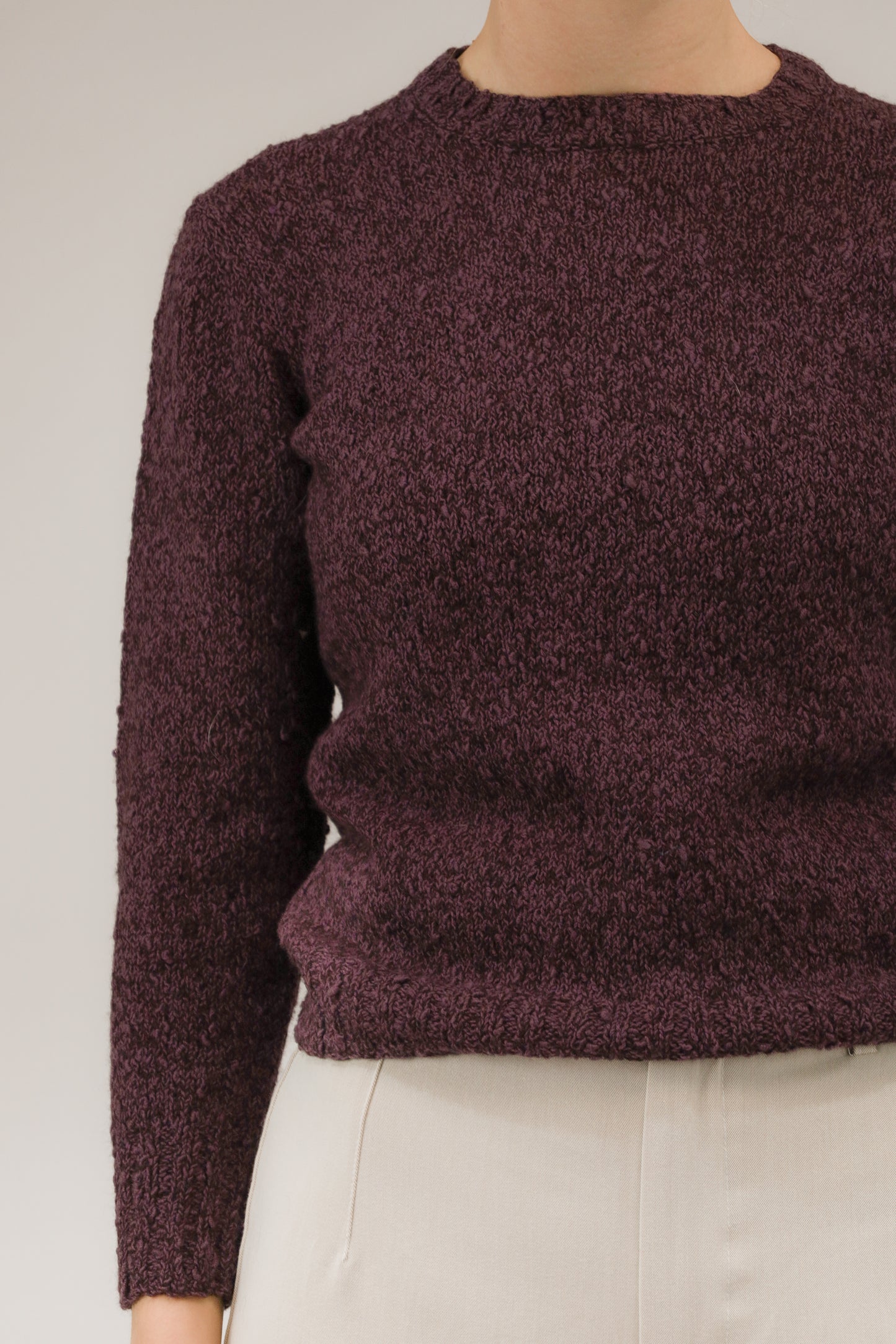 Detailopname van paarse melange trui, close-up van breisel en halslijn.