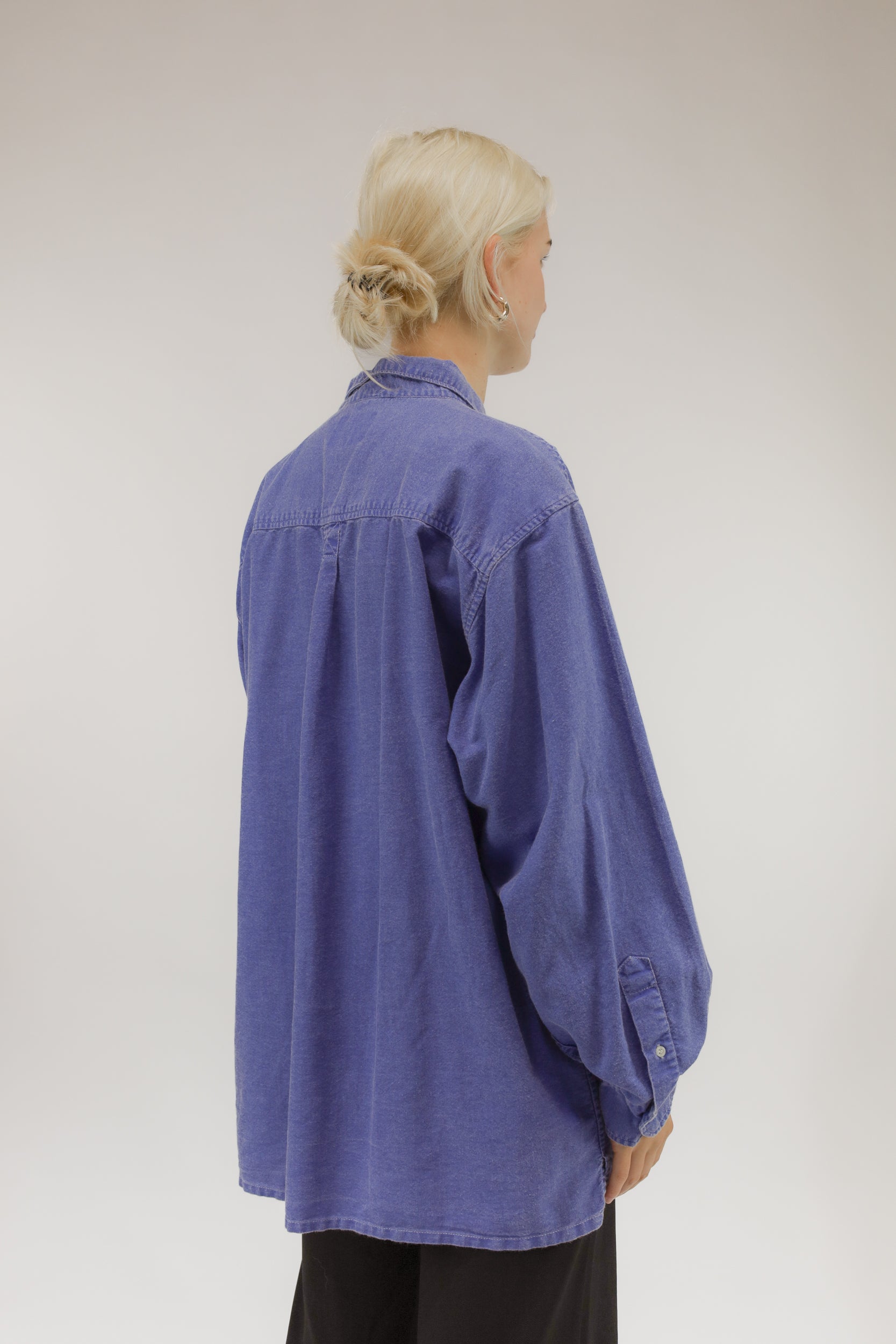 Model van achteren met vintage oversized blouse van dun katoen met denim verwassen effect.