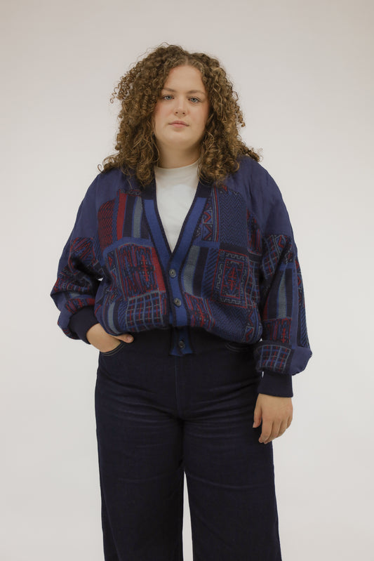 Vooraanzicht van model met vintage bomberjack in blauw en rood, deels gebreid en deels geweven.