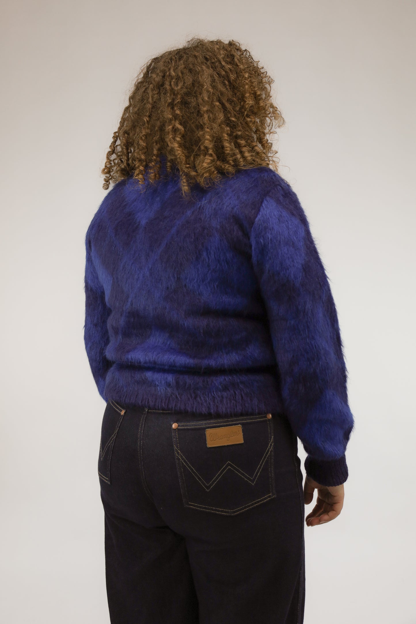 Achteraanzicht van model met lang vallende vintage trui in verschillende blauwtinten.