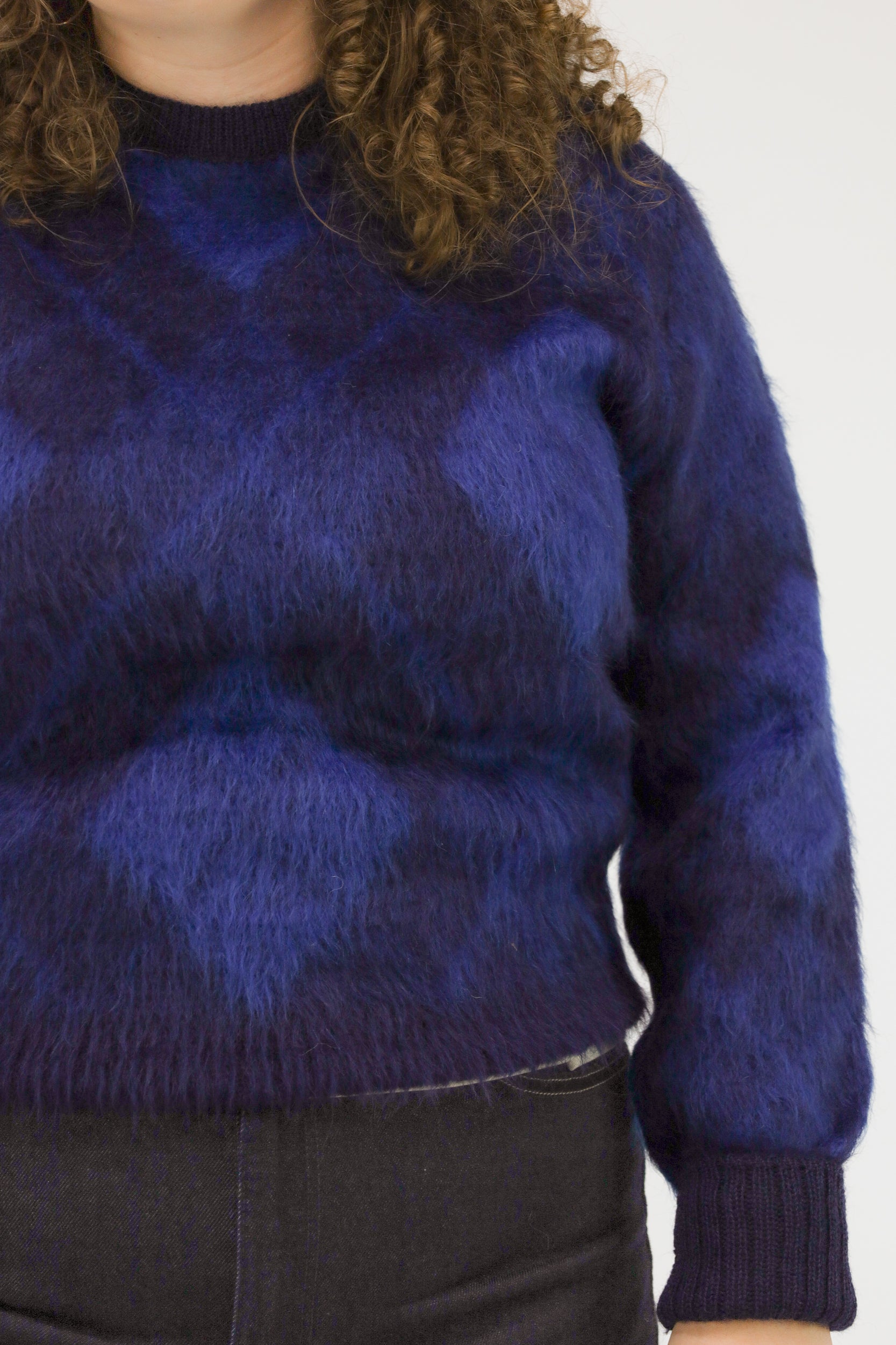 Detailopname van wolstructuur en kleurvlakken van de blauwe McGregor trui.