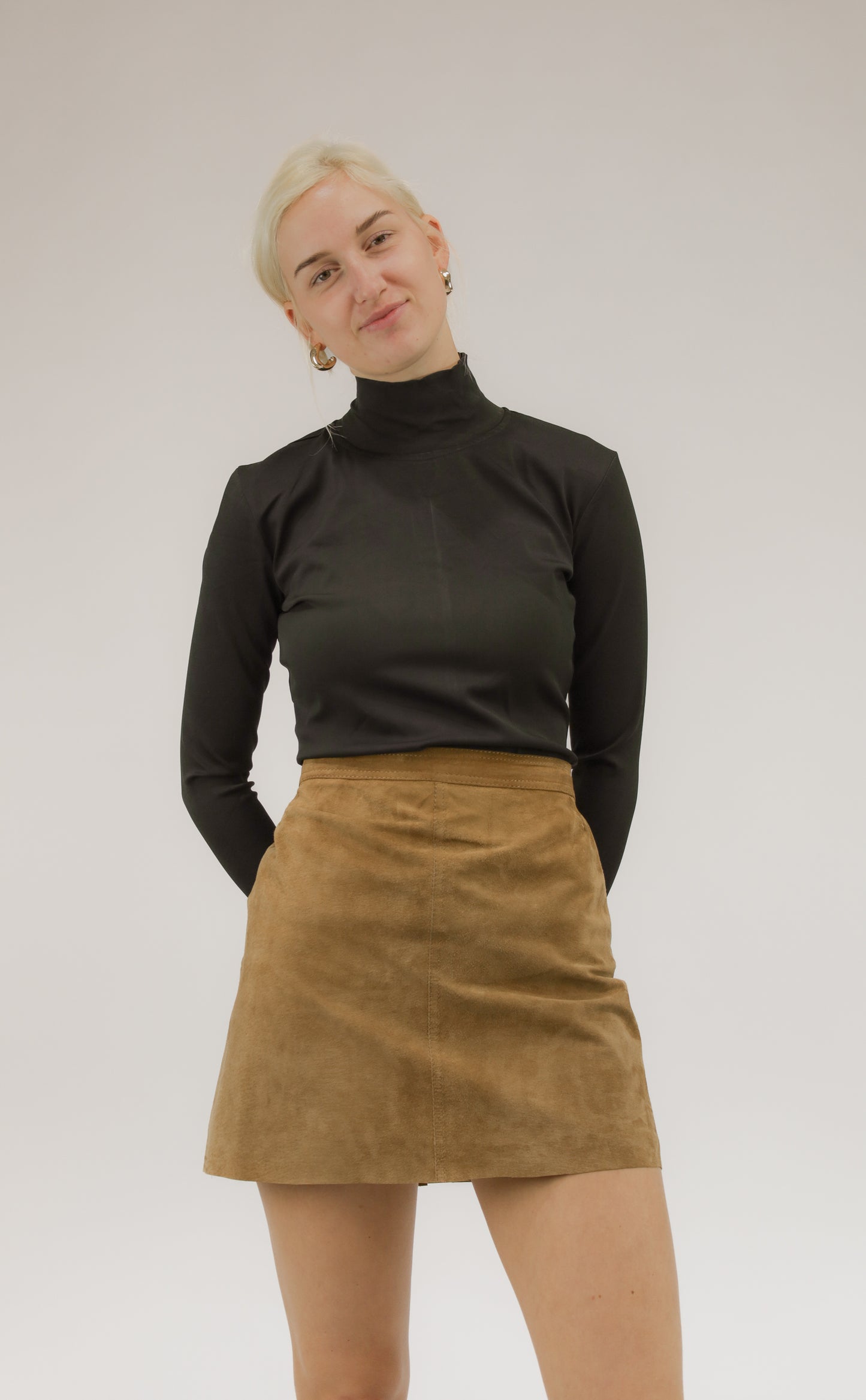 Model draagt vintage suède rok met soepele pasvorm – vooraanzicht.