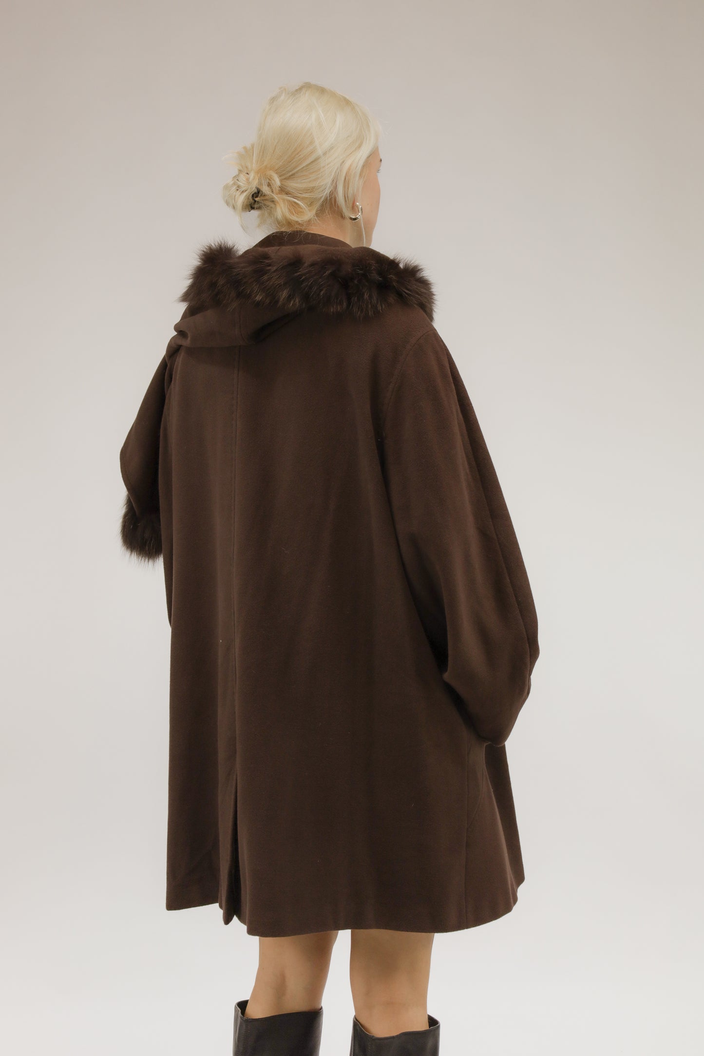 Model van achteren met bruine A-lijn mantel van wol en cashmere – afneembare capuchon zichtbaar.