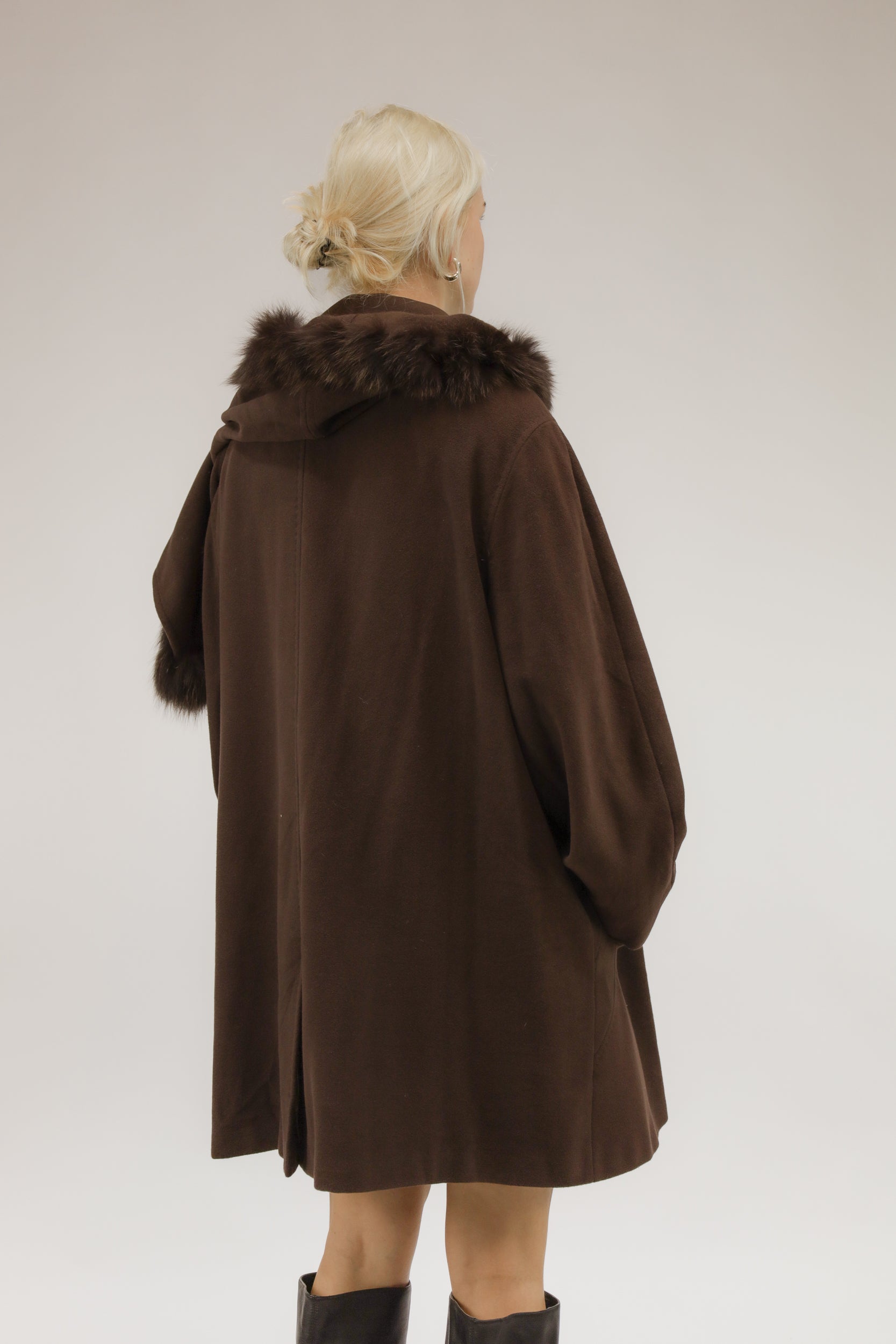 Model van achteren met bruine A-lijn mantel van wol en cashmere – afneembare capuchon zichtbaar.