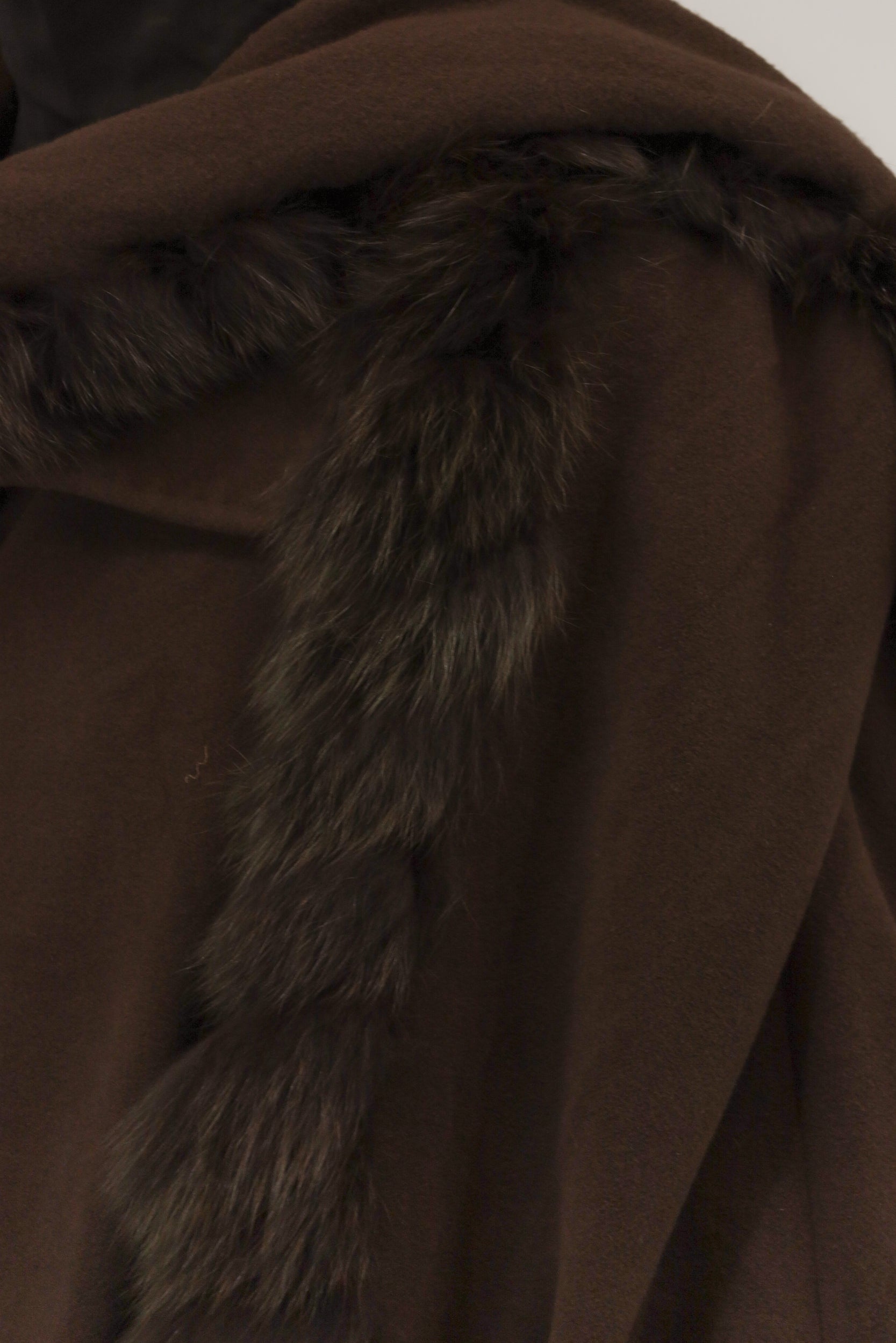 Close-up van model met wollen cashmere mantel – detail van nepbontkraag en zachte stofstructuur.