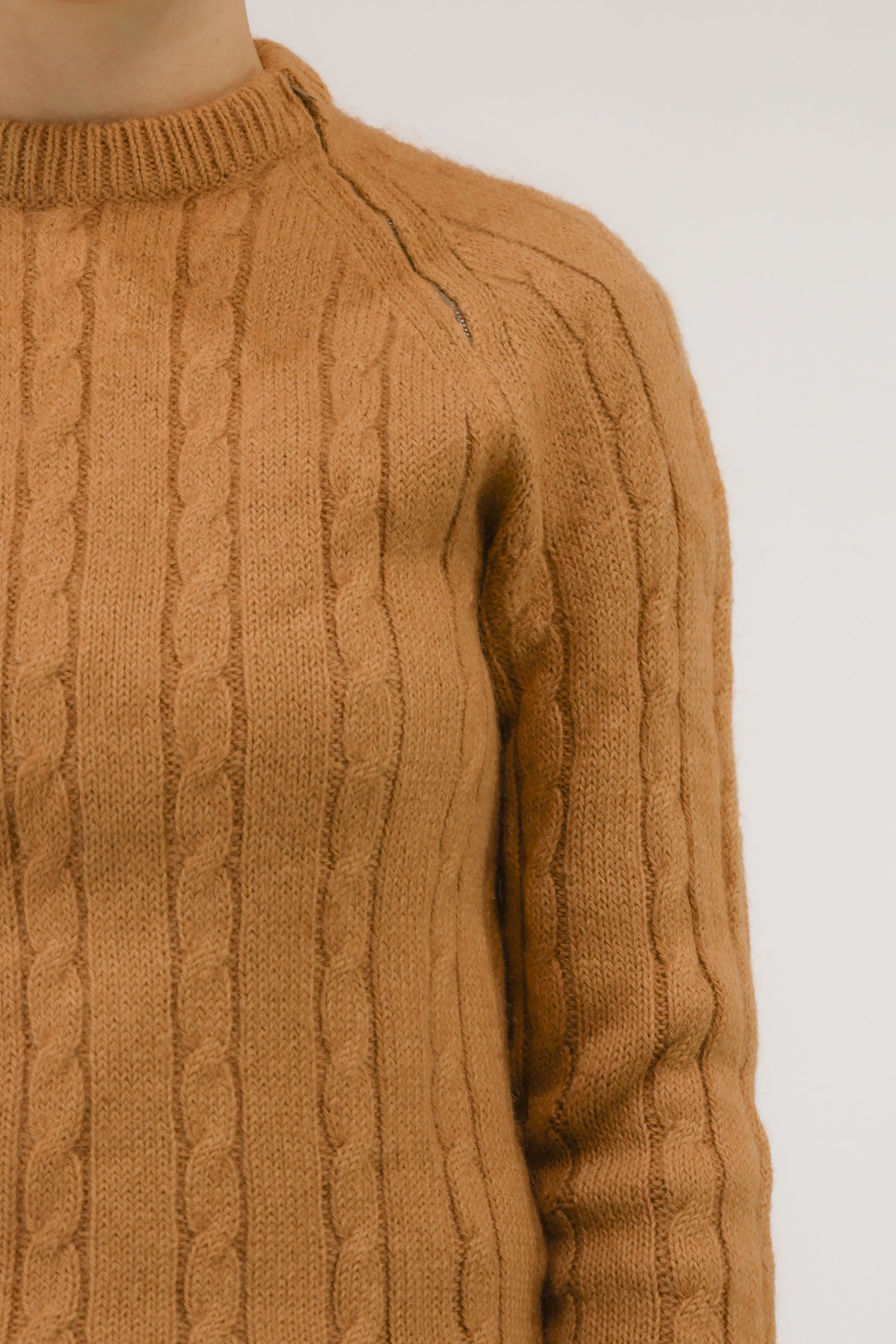 Detailopname van kabelbreisel en ritsdetail op schouder.