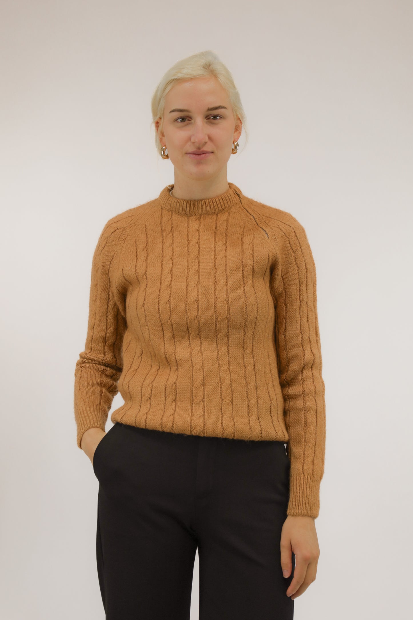 Vooraanzicht van model met cognacbruine vintage trui met kabeldessin en schouderr it s.