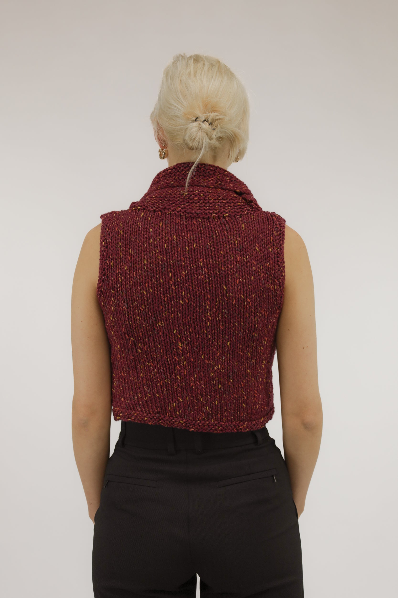 Achteraanzicht van model met mouwloze vintage top in oranje-zalmtinten.