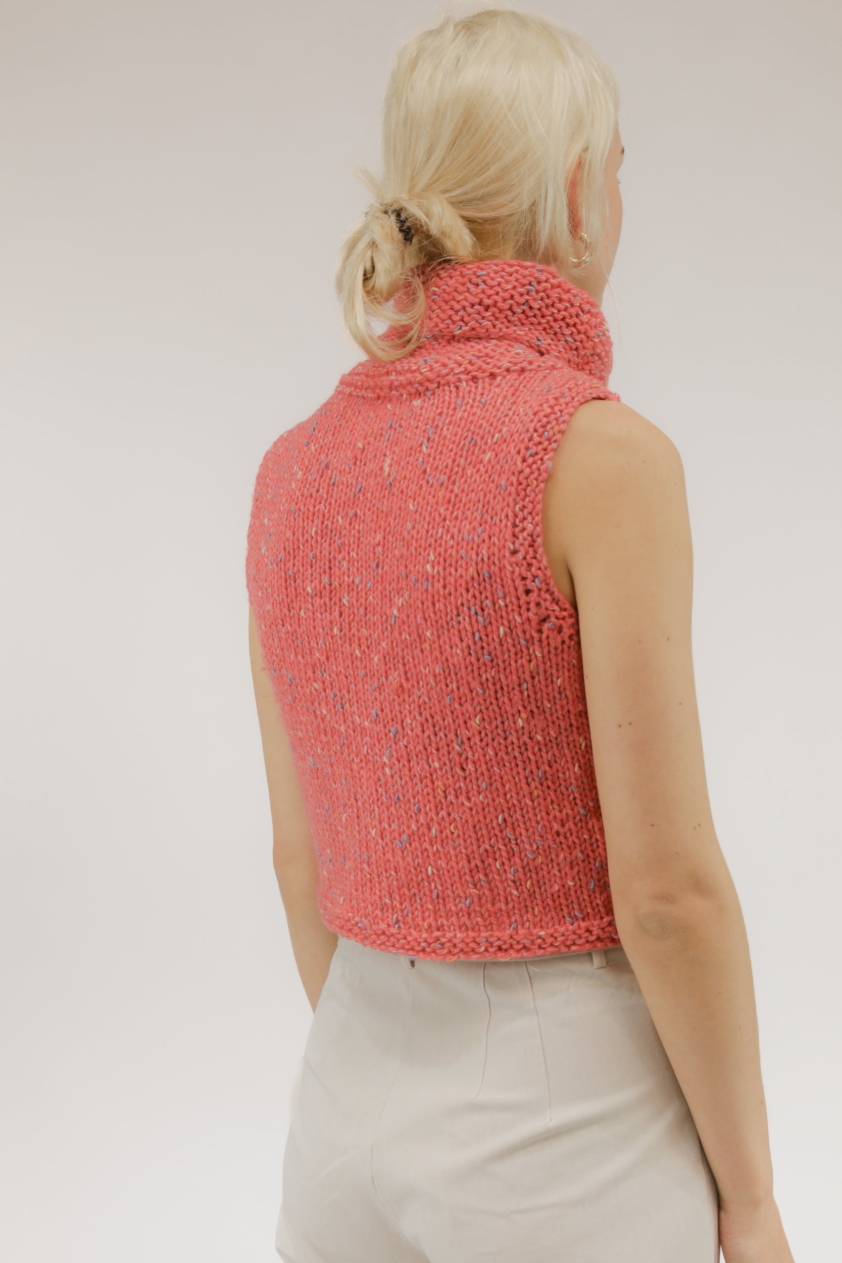 Achteraanzicht van model met mouwloze vintage top in oranje-zalmtinten.