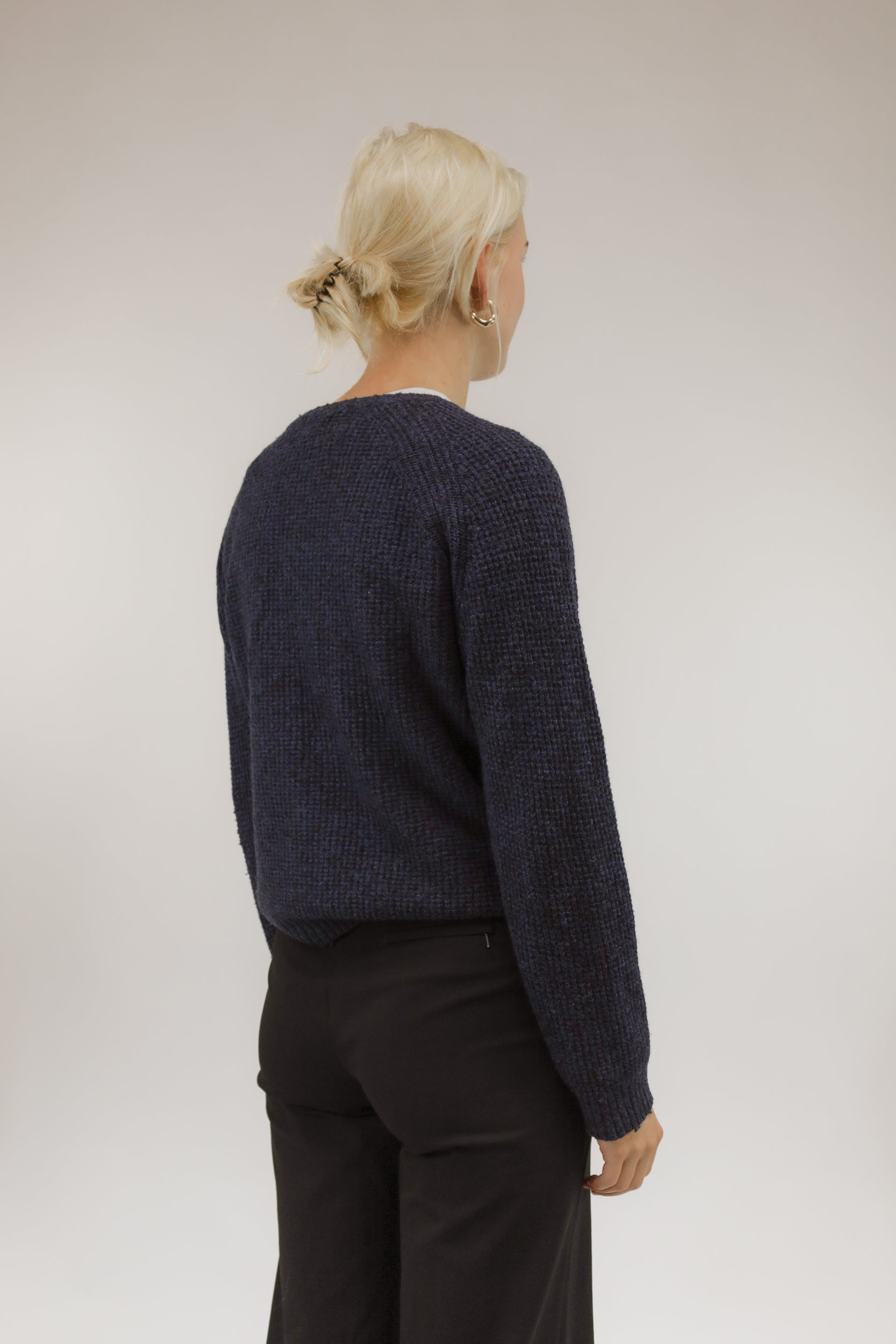 Model van achteren met donkerblauwe basic trui van Lee – subtiel blokjesmotief over de rug zichtbaar.
