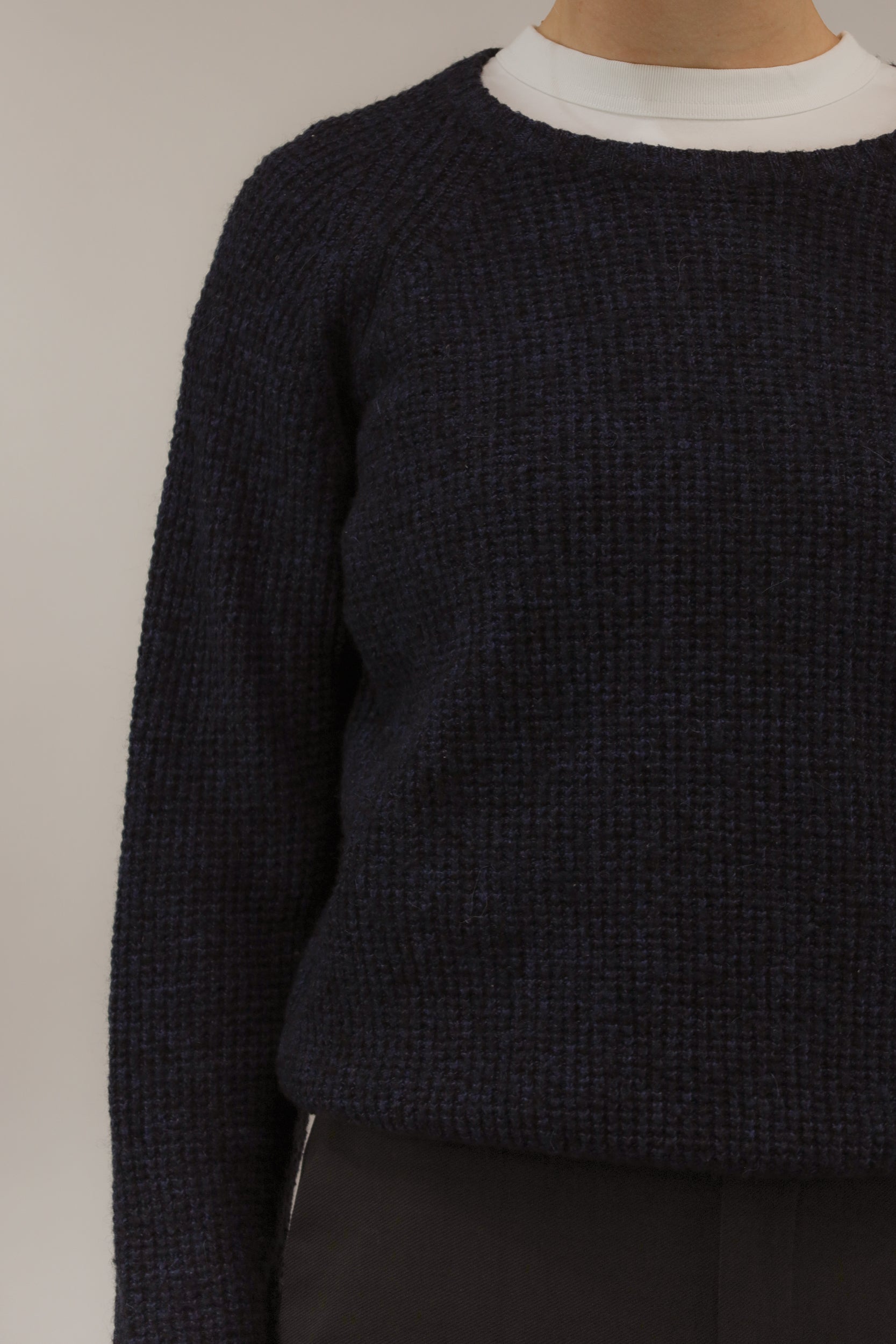 Close-up van model met donkerblauwe trui van Lee – detail van fijn ingebreid blokjespatroon.