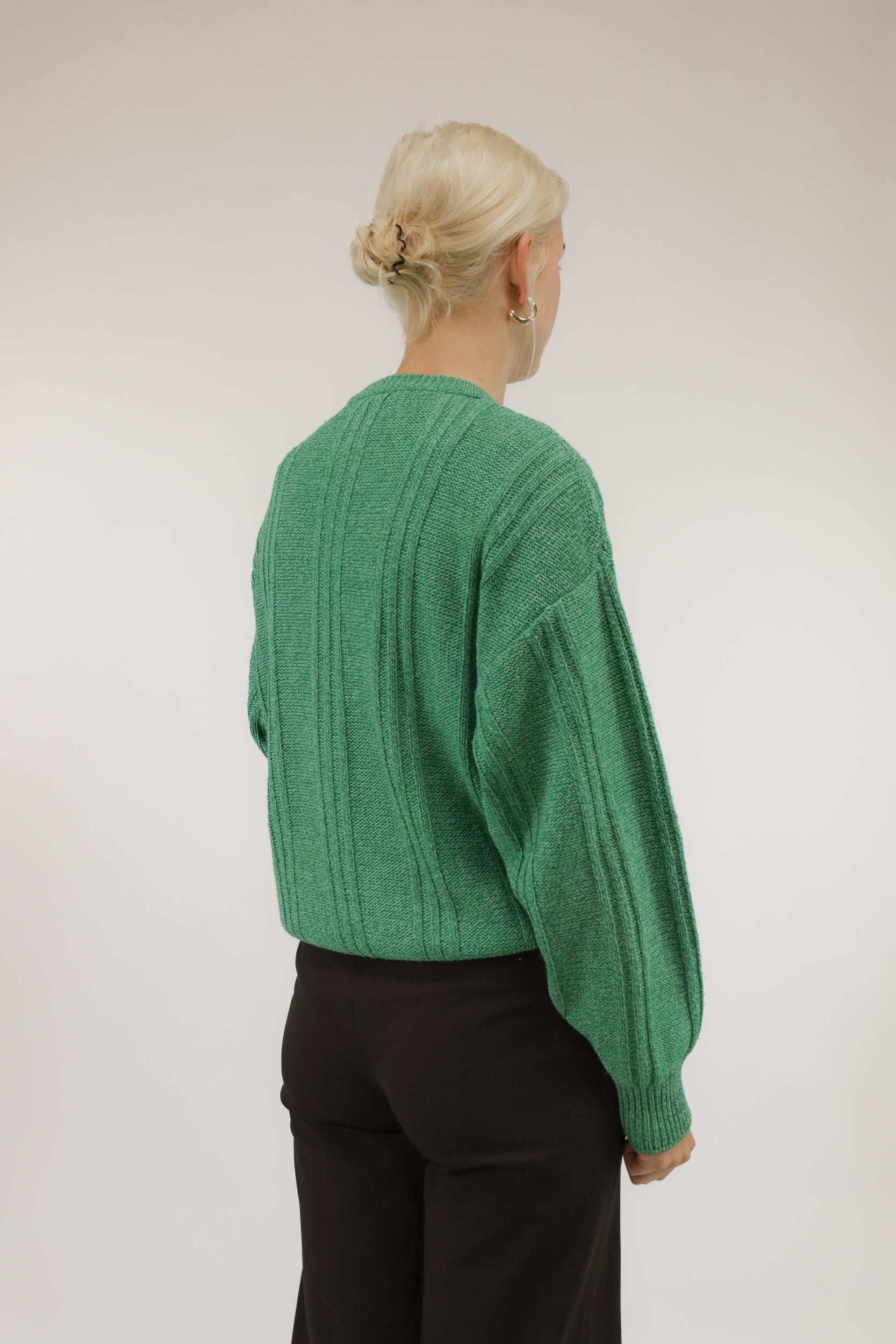 Achteraanzicht van model met ruimvallende groene vintage trui van katoenmix.