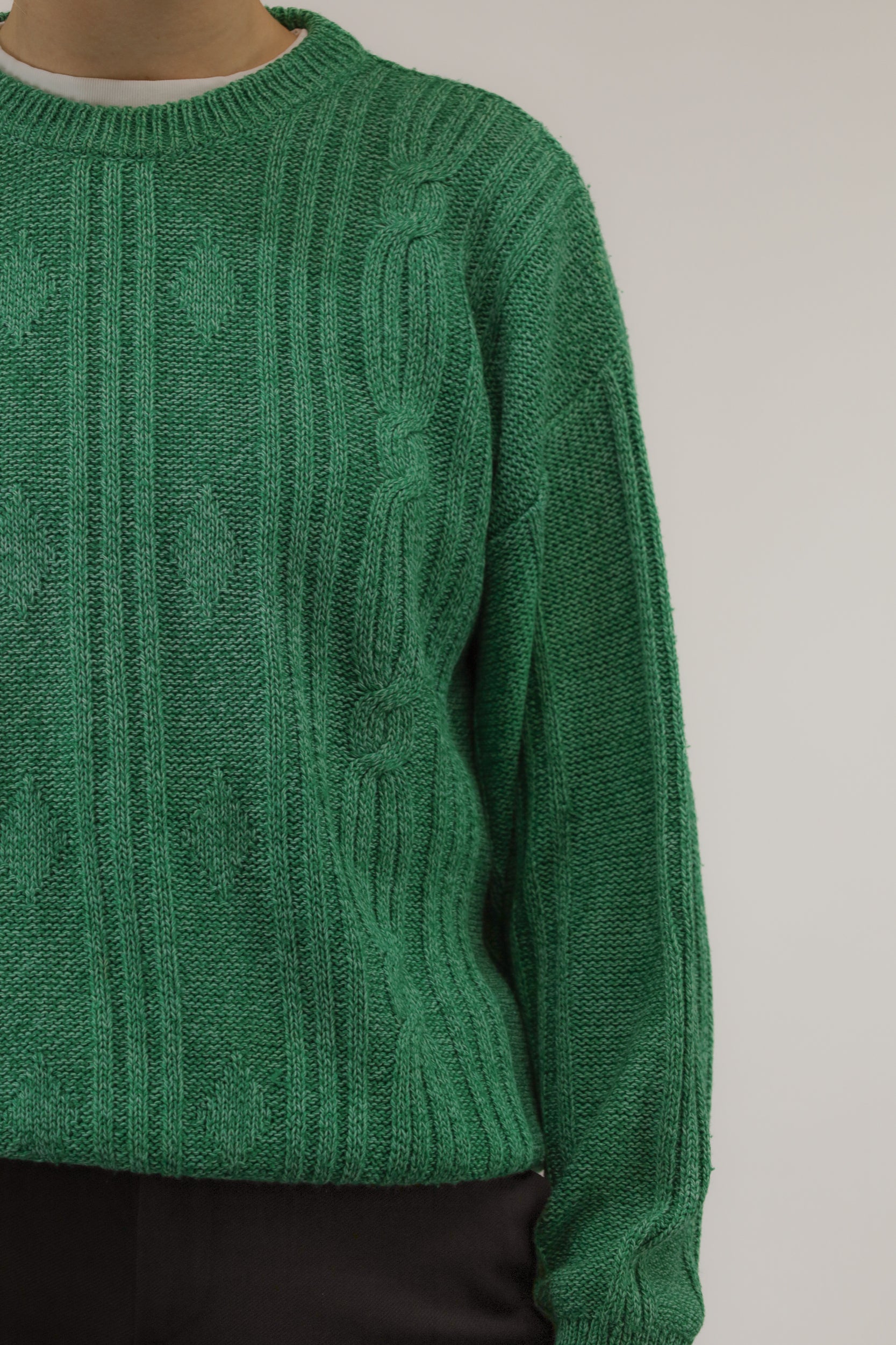 Detailopname van melange garen en ingebreid kettingpatroon in wit en groen.