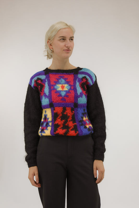 Model draagt vintage mohair trui met zwarte basis en ingeweven blokkenpatroon in diverse kleuren – vooraanzicht.