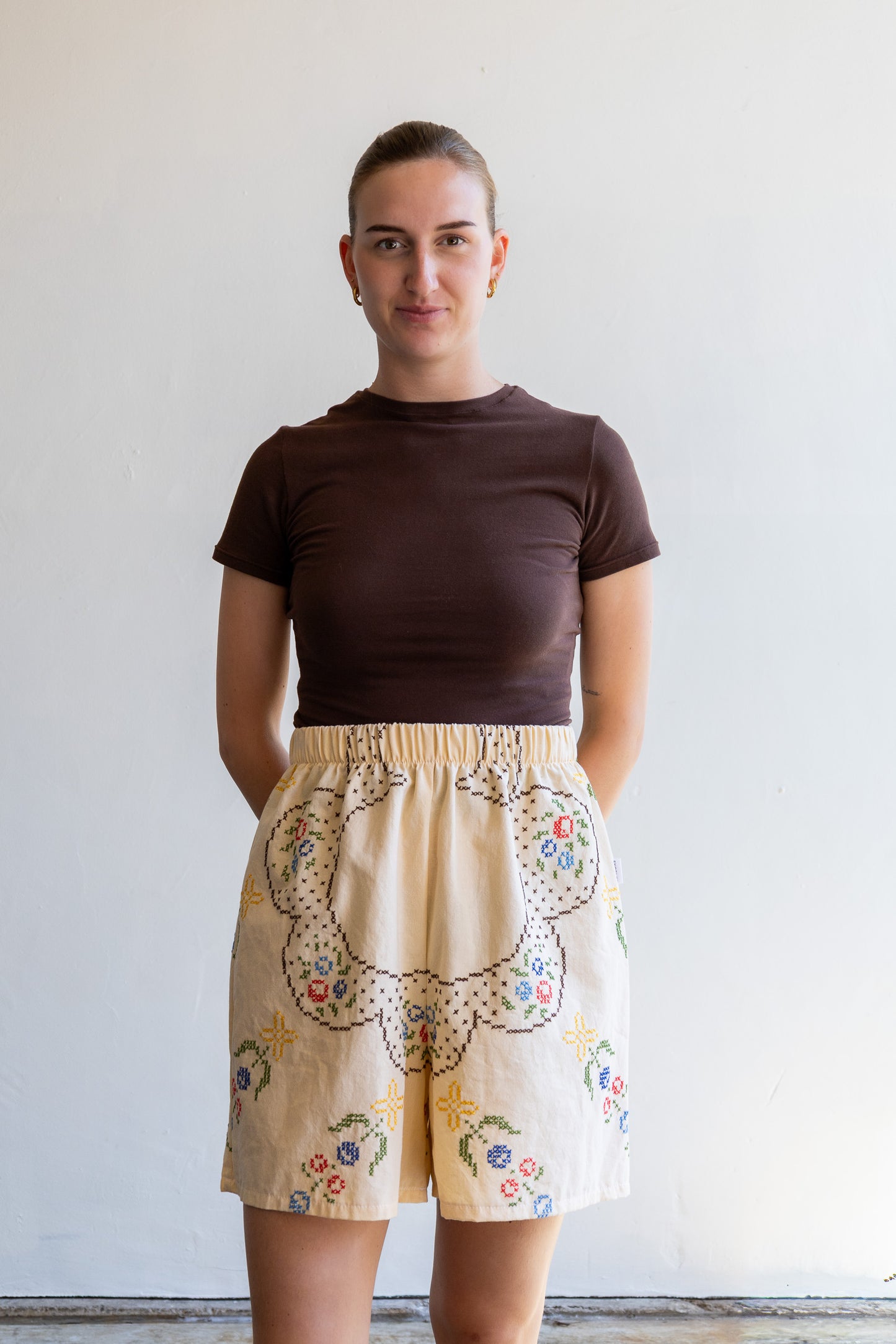 Handgemaakte short van een geborduurd vintage tafelkleed met elastische tailleband en kruisstekenmotief.
