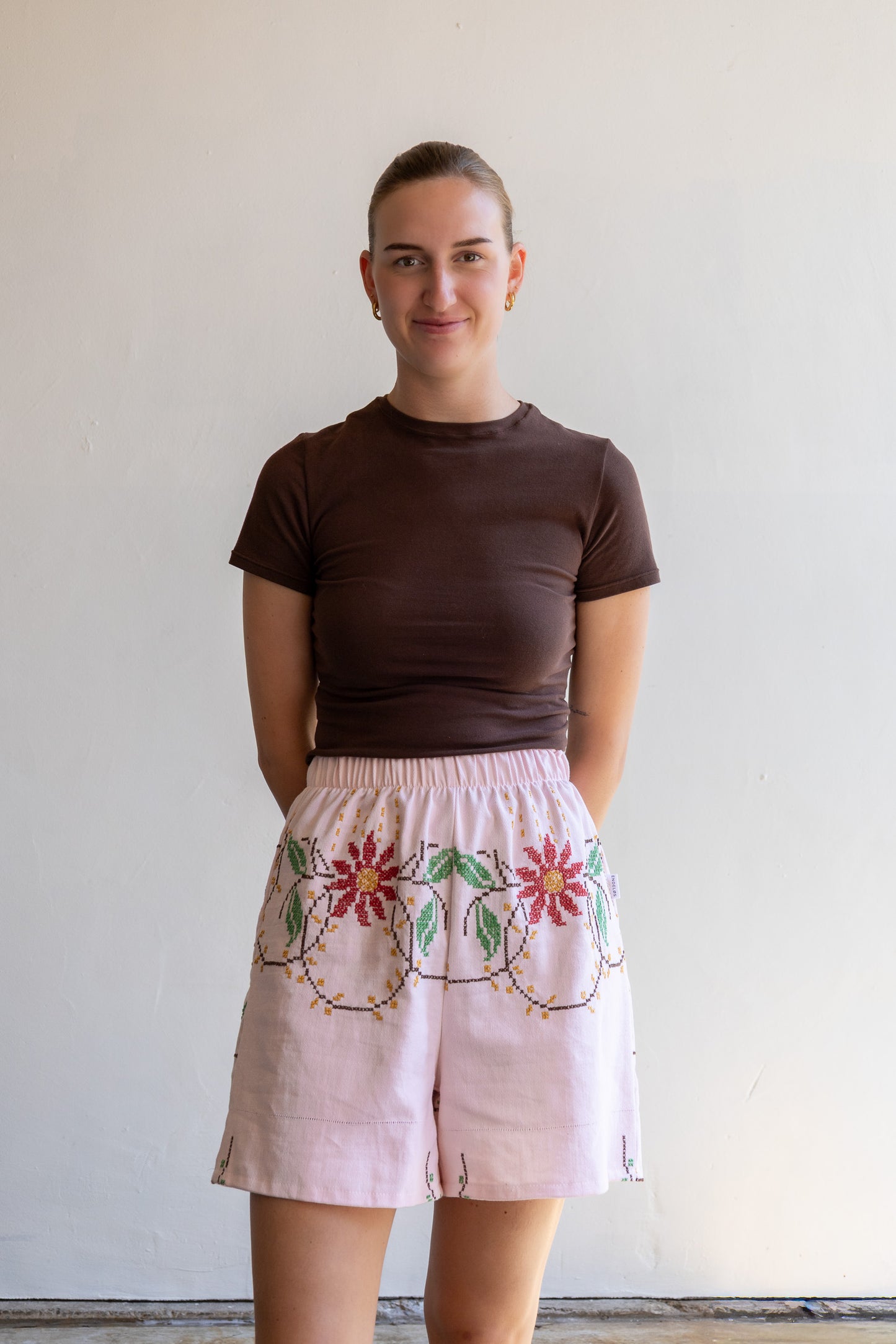 Handgemaakte short van een geborduurd vintage tafelkleed met elastische tailleband en kruisstekenmotief.