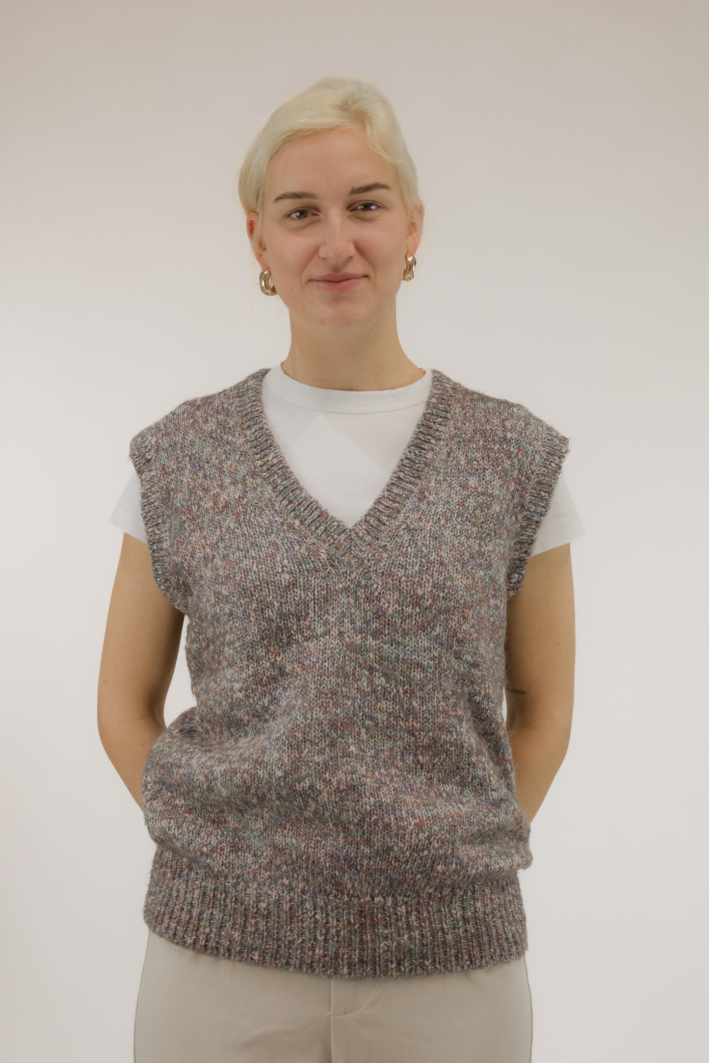 Model draagt vintage spencer van melange garen in rood- en paarstinten – vooraanzicht, V-hals.