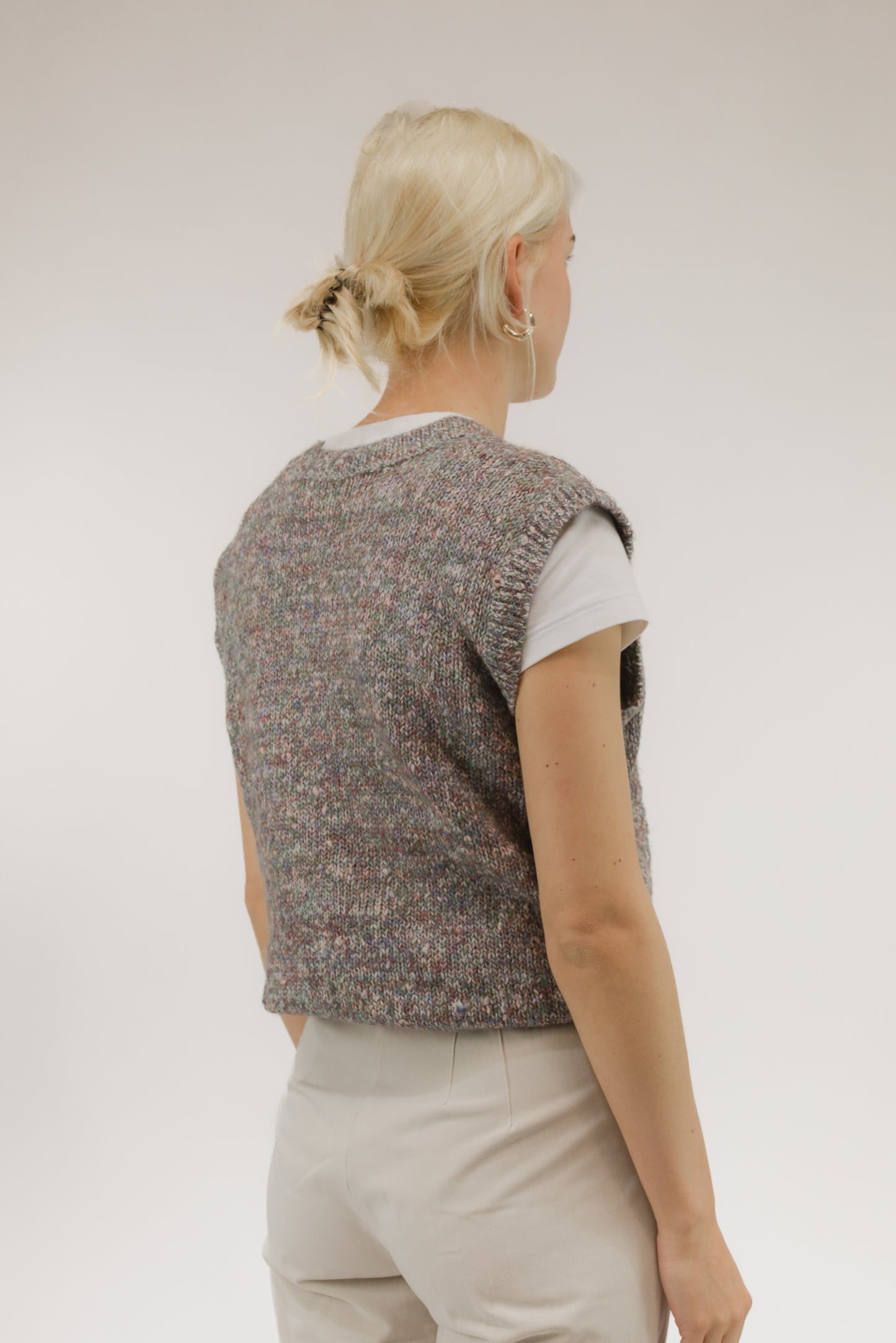 Model van achteren met vintage spencer in rood en paars melange – zachte breistructuur zichtbaar.